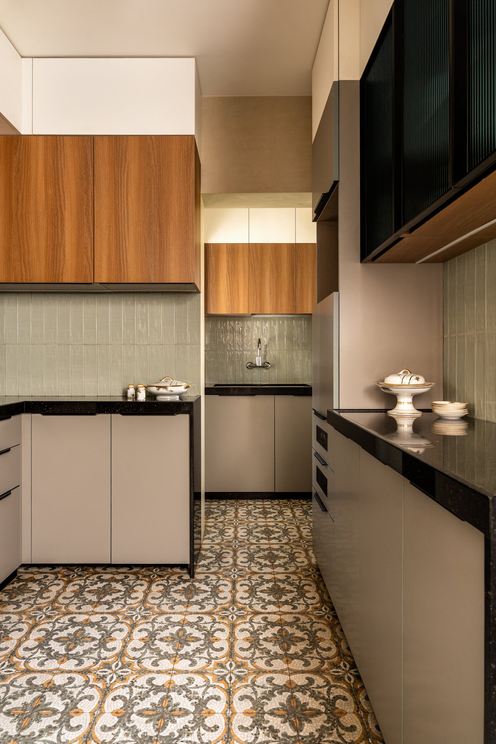 The kitchen, its densely patterned encaustic-style floor grounding a palette of taupe, sage, and warm wood