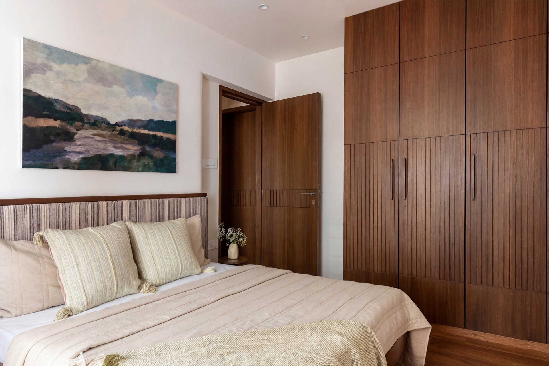 The daughters' bedroom introduces the cooler side of the palette, anchored by a striped headboard and a landscape painting