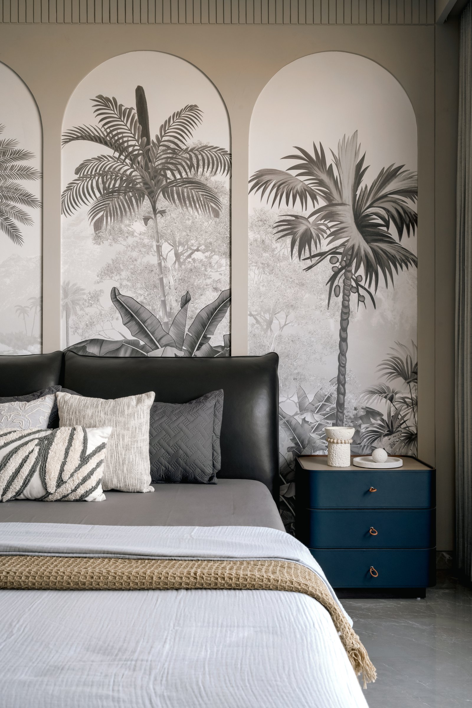The primary bedroom, its grey-toned tropical mural set within three arched panels behind the bed