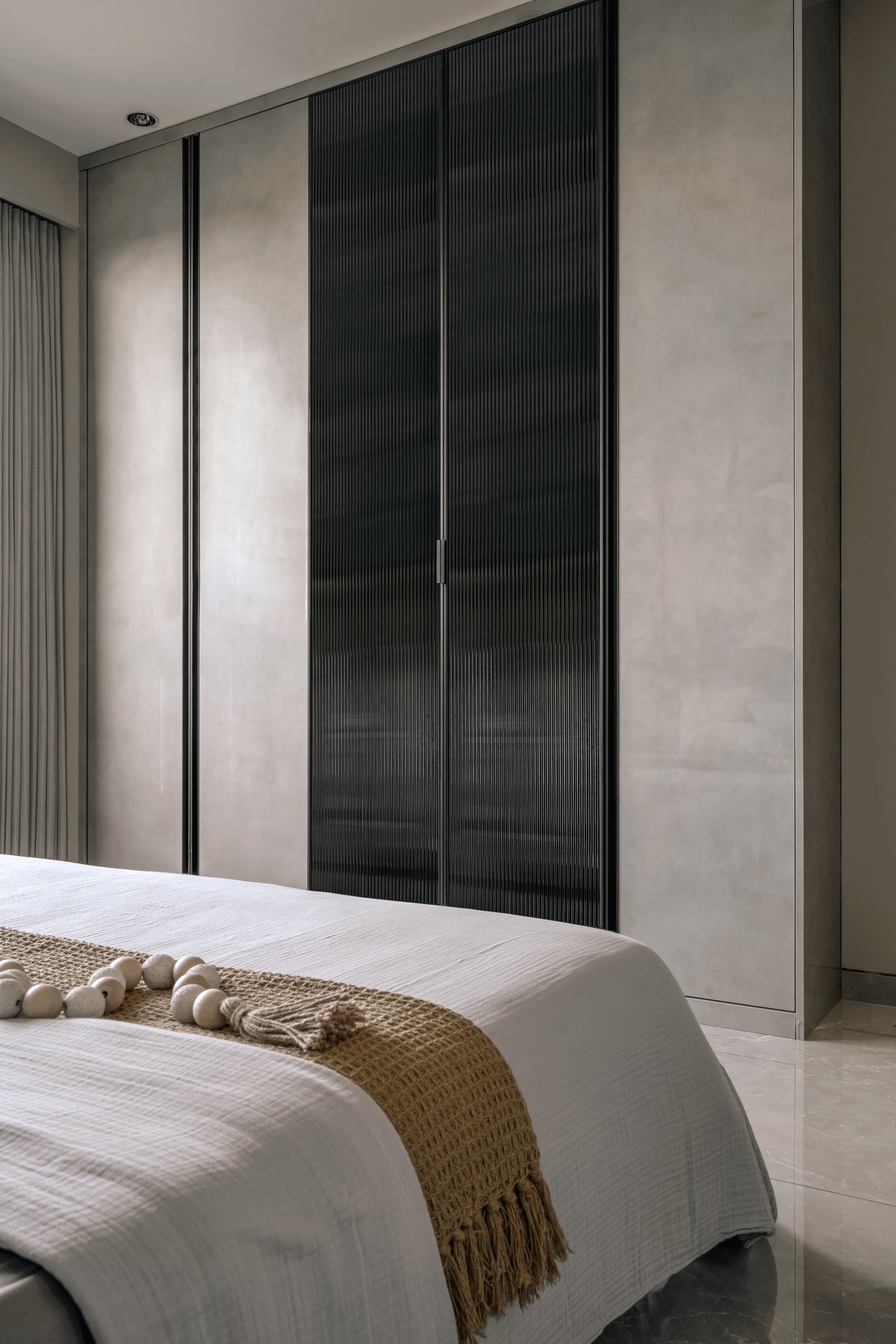 A full-height wardrobe composed as a triptych, with reeded dark glass at its centre