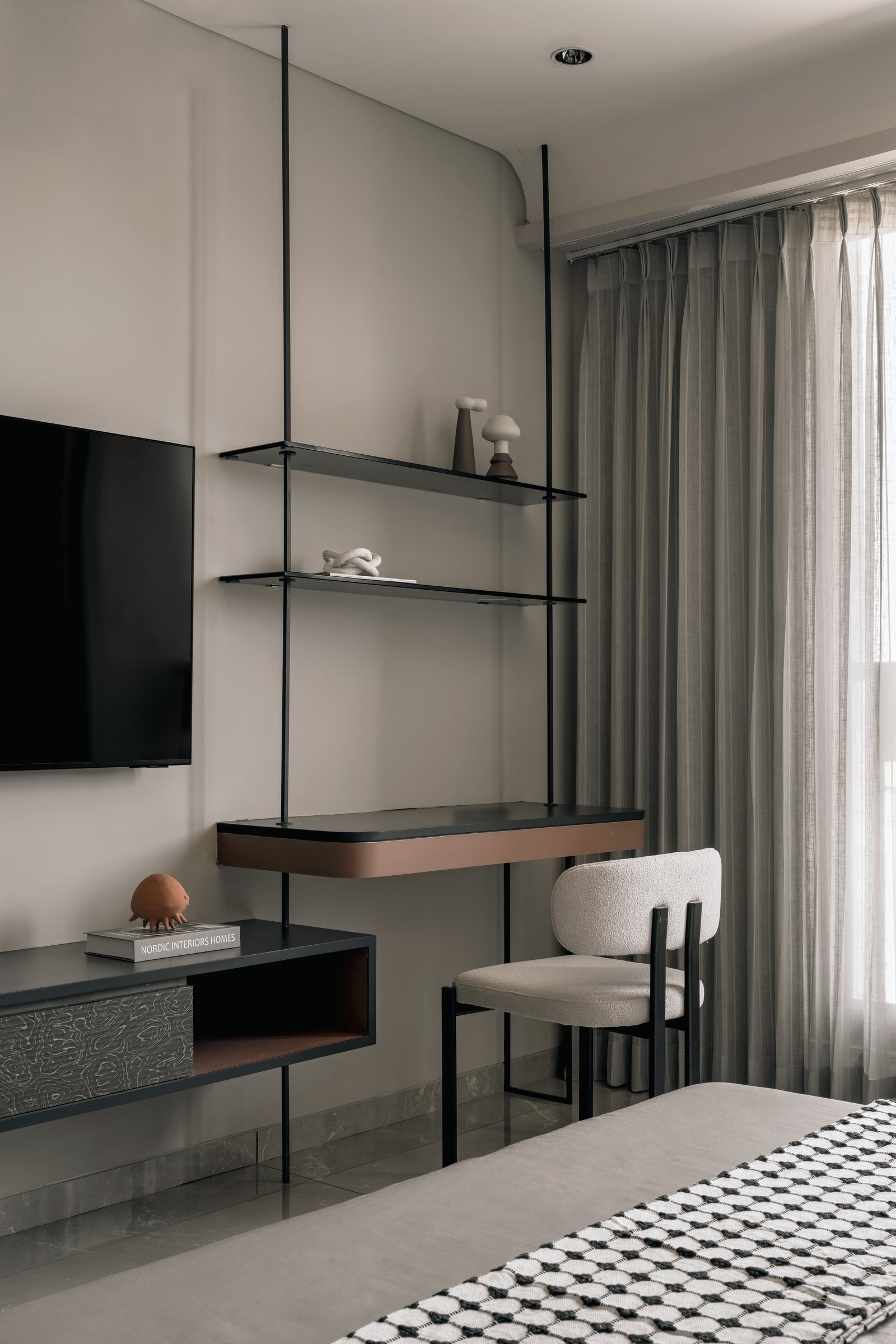 A study nook composed as a slim dark metal frame, with a bouclé chair and a sliver of veneer on the console