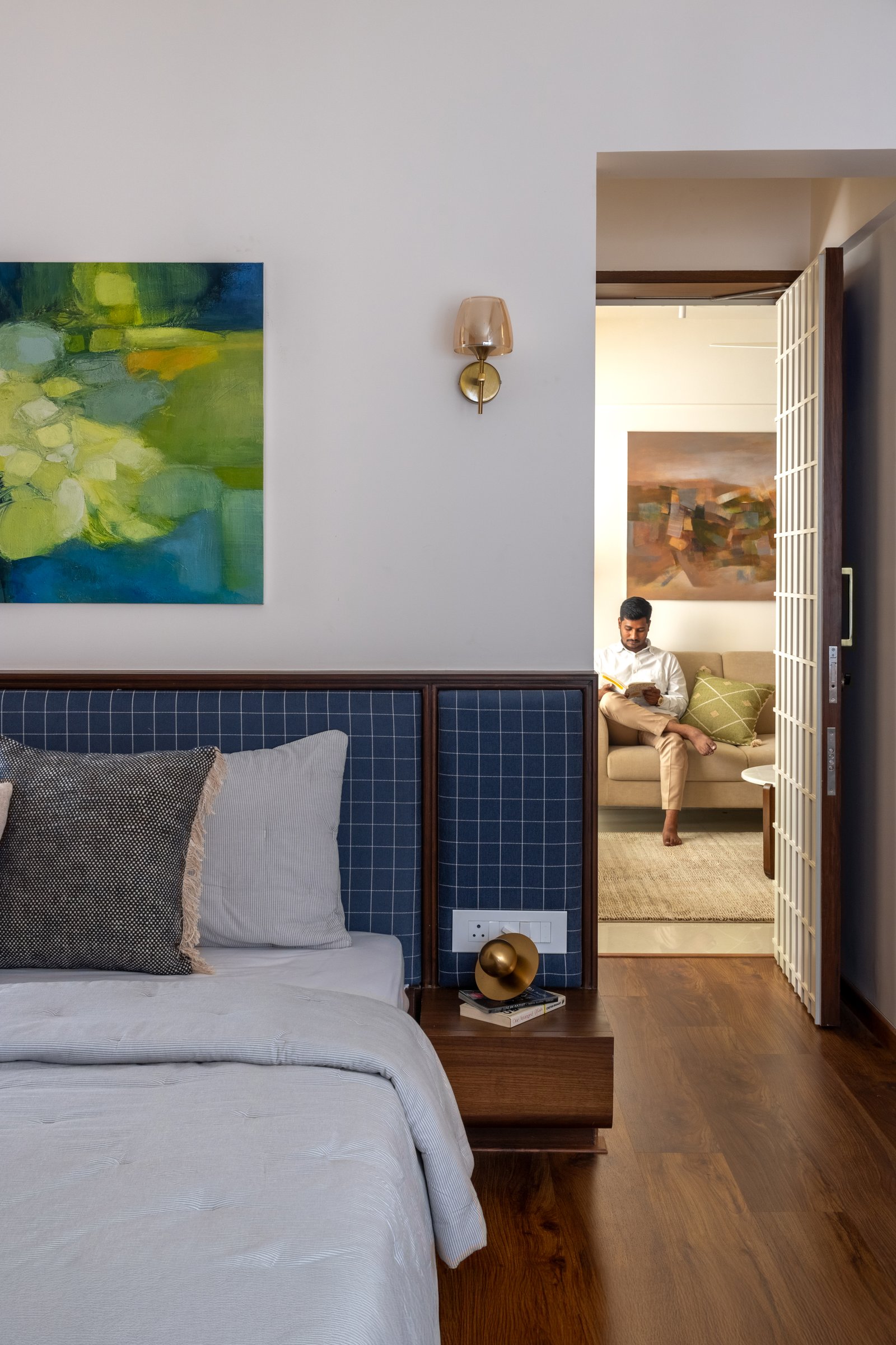 The bedroom opens directly into the living room, its threshold marked by a slim gridded panel