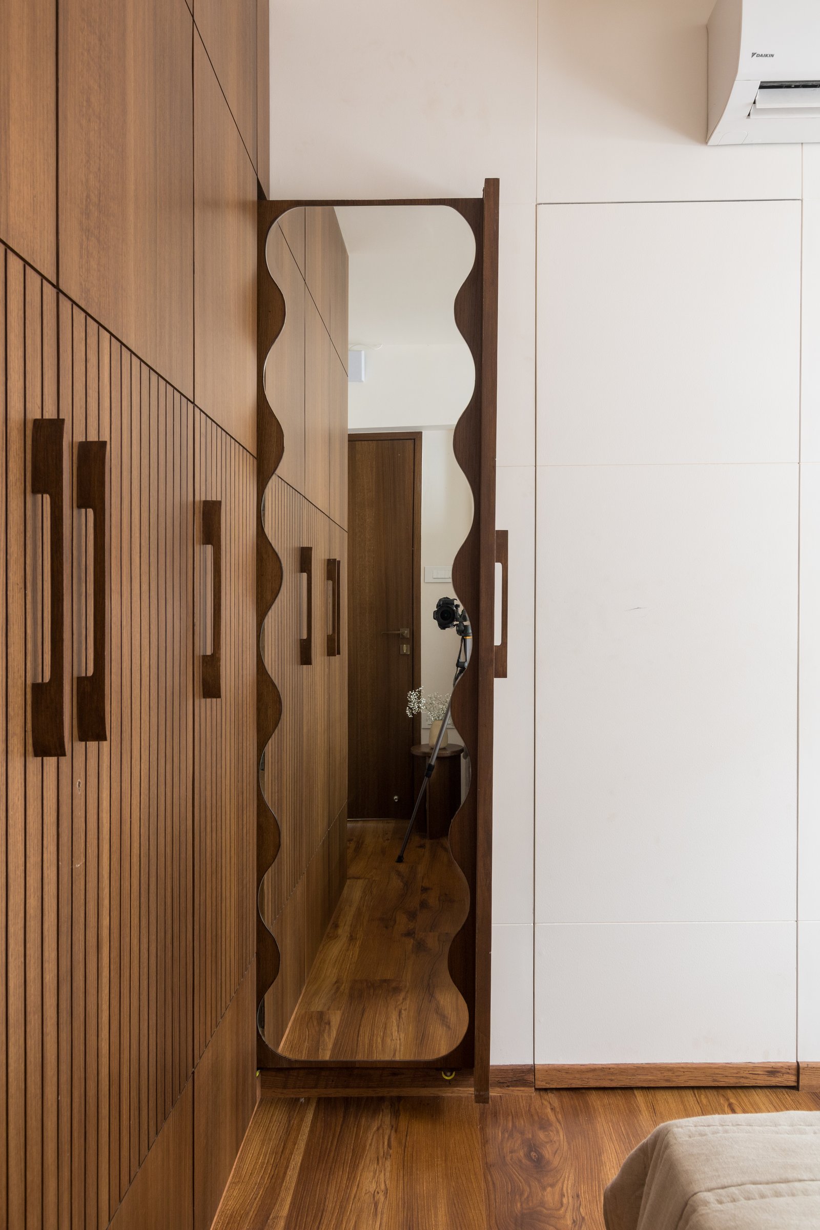 A wavy scalloped mirror frame defines the dressing zone with a single expressive gesture