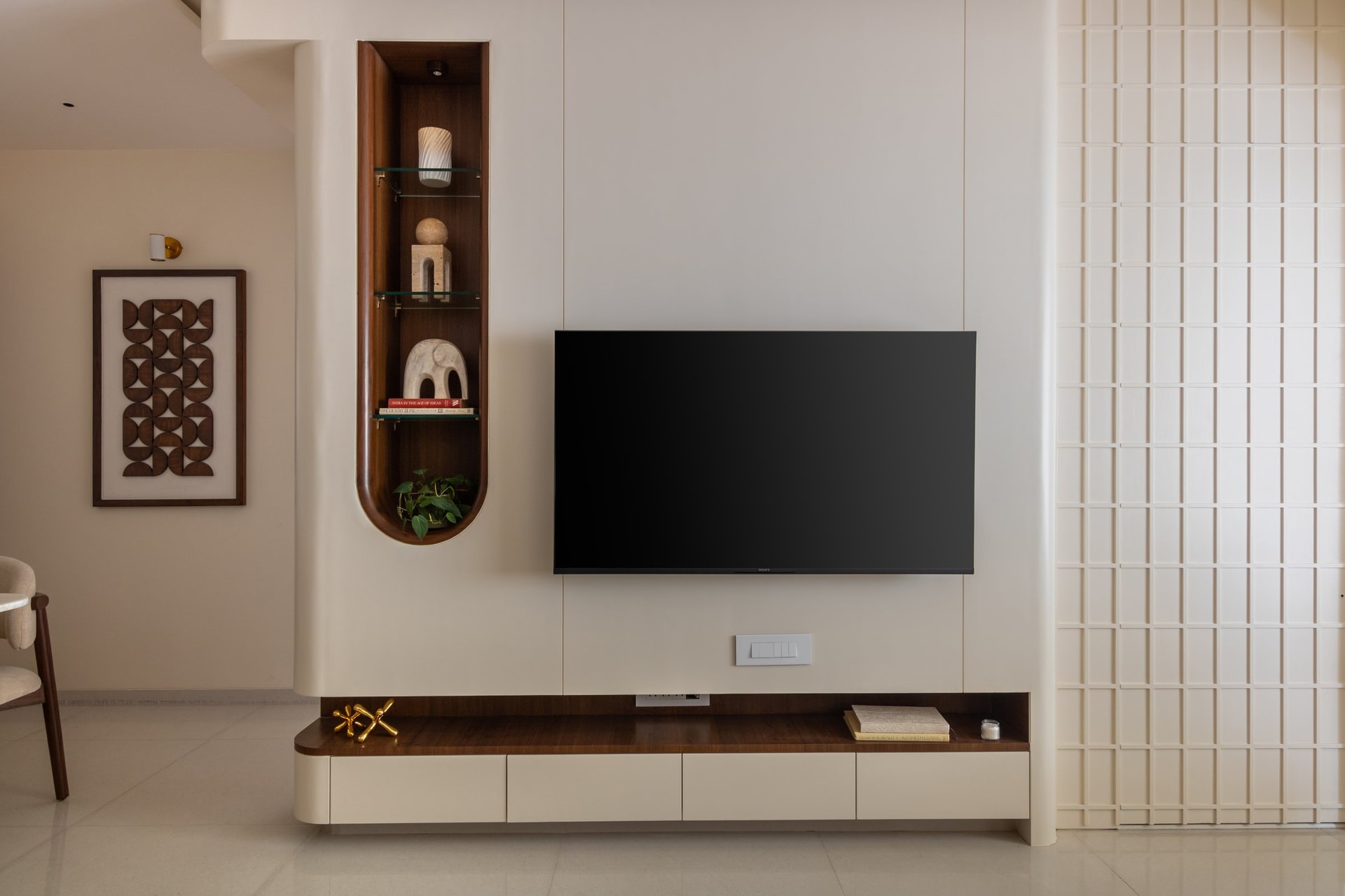 The media wall seen head-on: a tall veneered arched niche paired with pale cabinetry that keeps the television flush