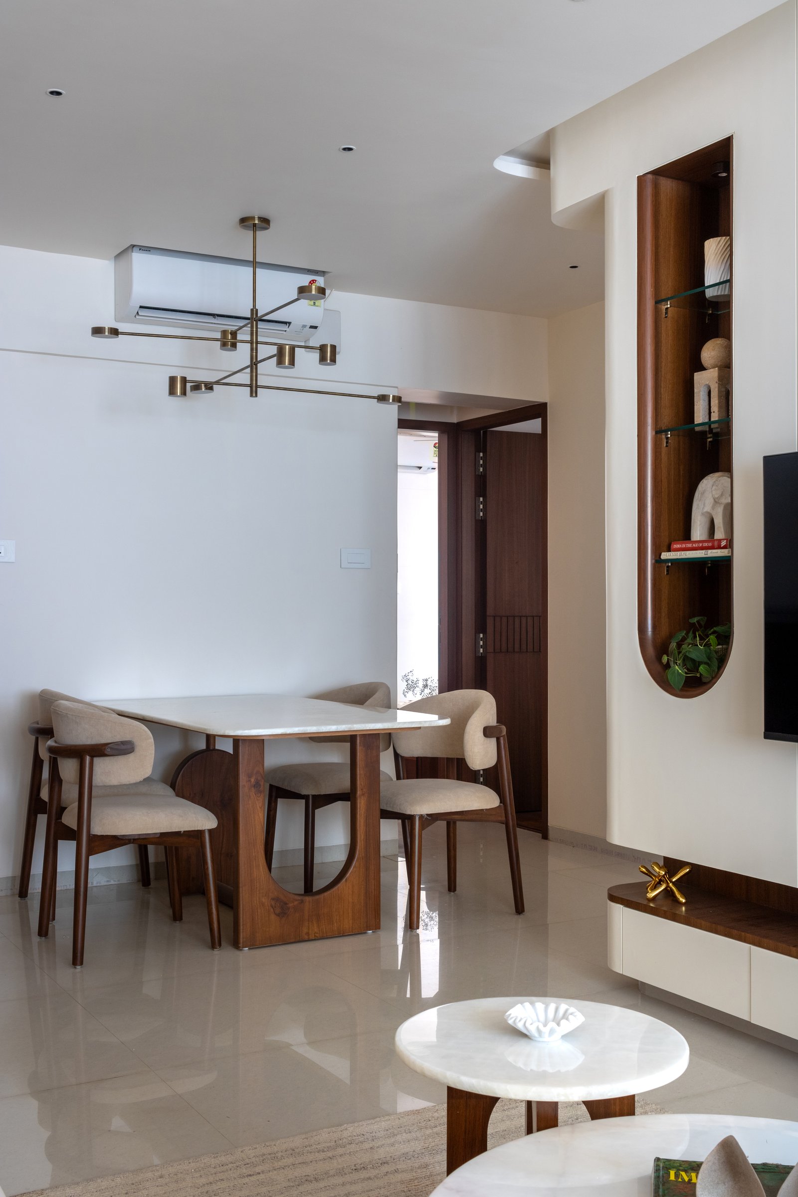 The dining zone sits in easy dialogue with the living room, framed by a slim brass-toned linear chandelier