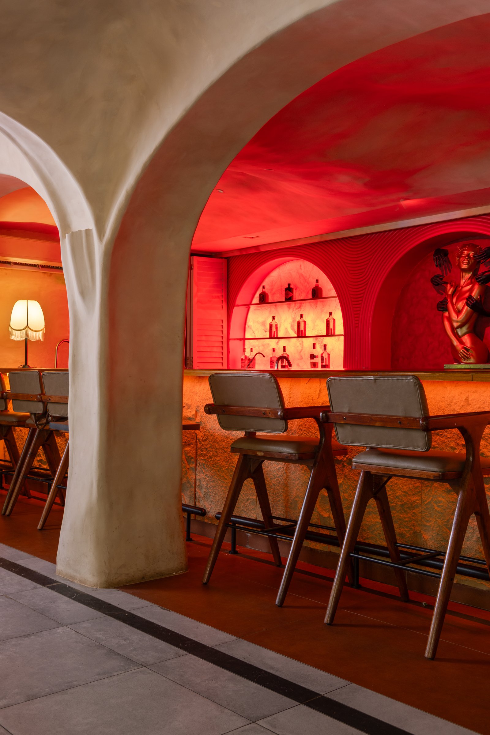 The bar by night, arched niches of backlit liquor revealed behind the retracted shutters