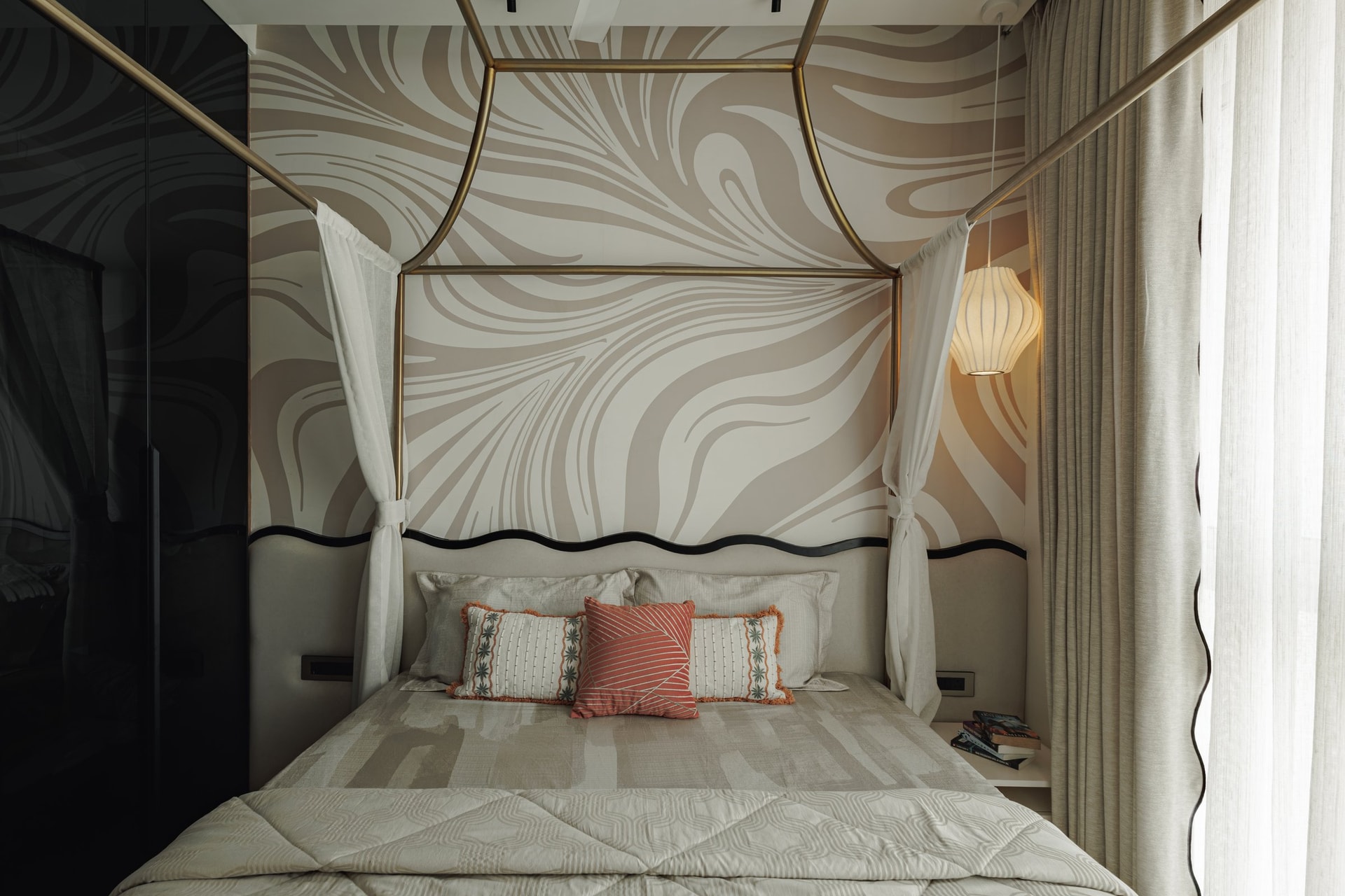 A bedroom in softer graphic territory, its swirling pale mural set behind an upholstered headboard with a dark undulating trim