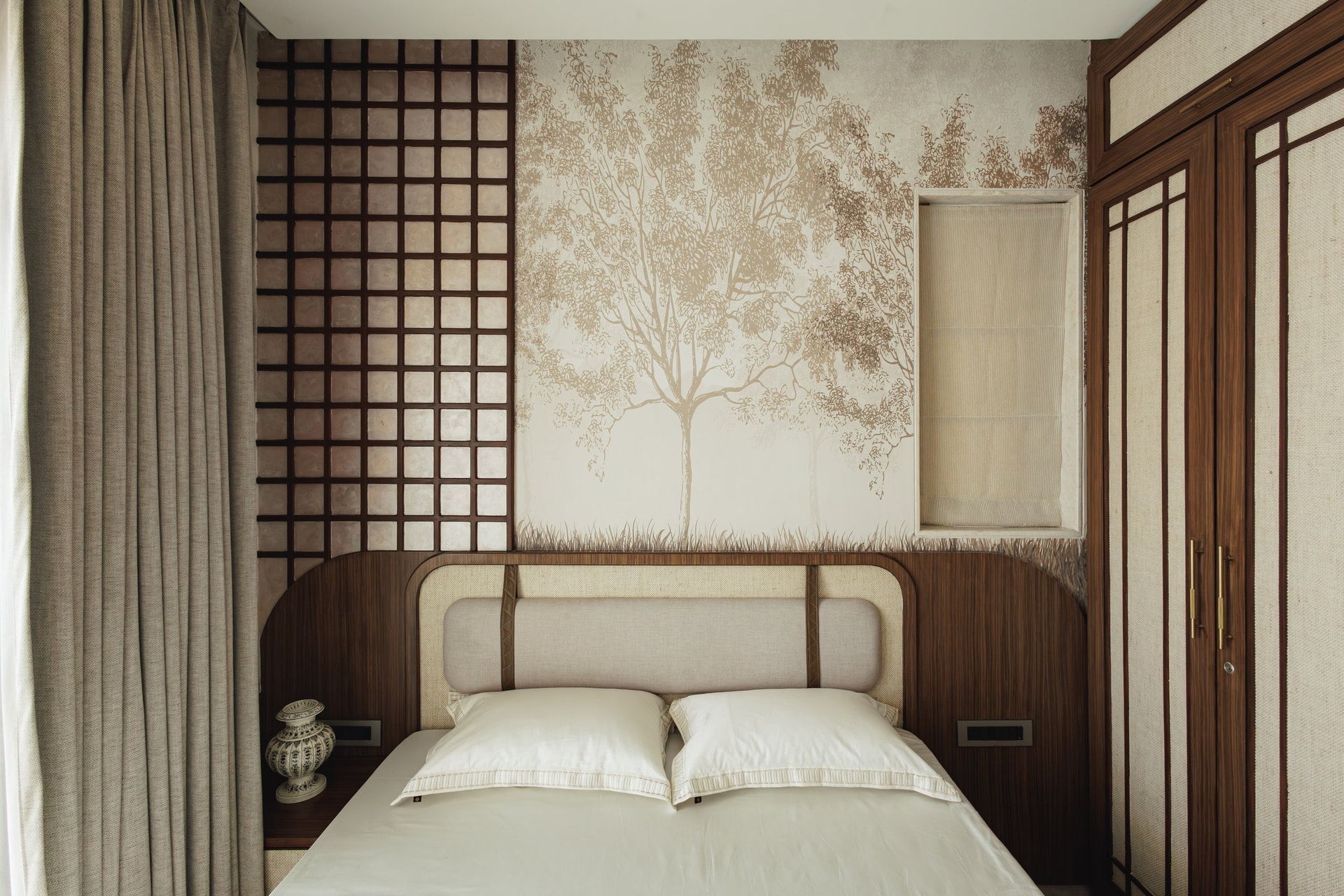The second bedroom, where a sepia tree mural and a tall dark timber grid screen frame the bed