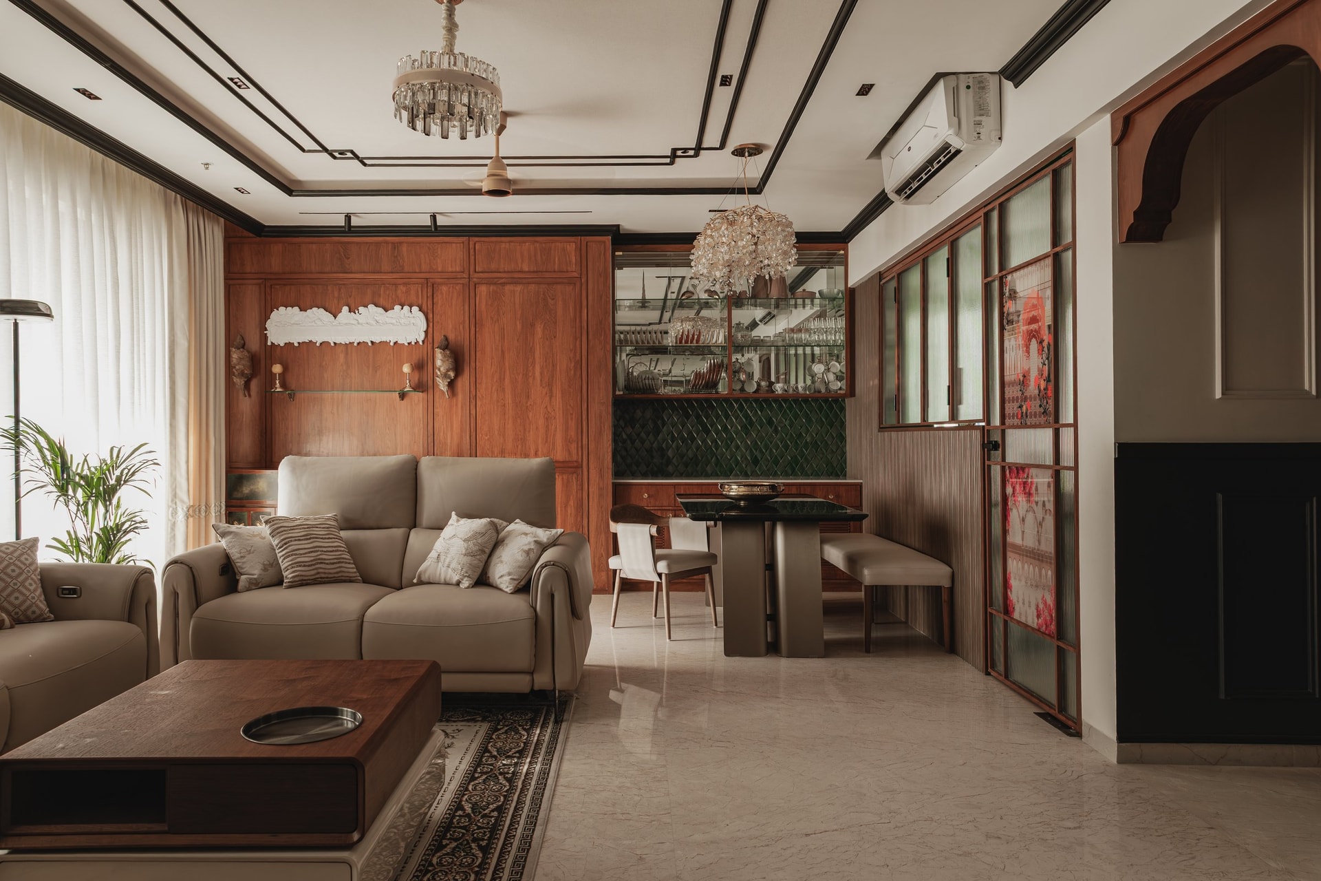 The living room, anchored by a walnut-panelled wall and a pair of taupe upholstered sofas beneath a formal tray ceiling