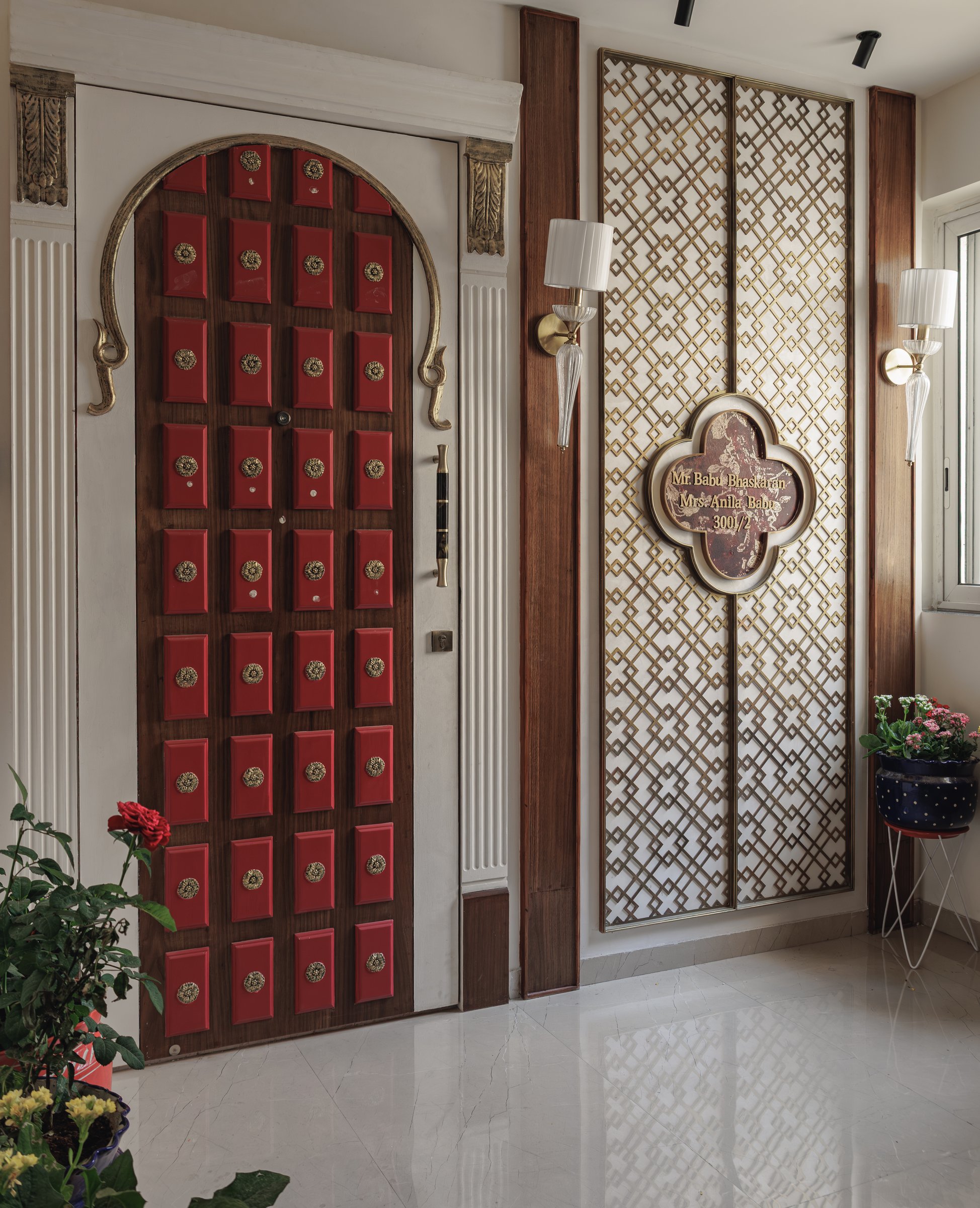 The main entrance, framed by fluted pilasters and a brass fretwork name-plaque screen