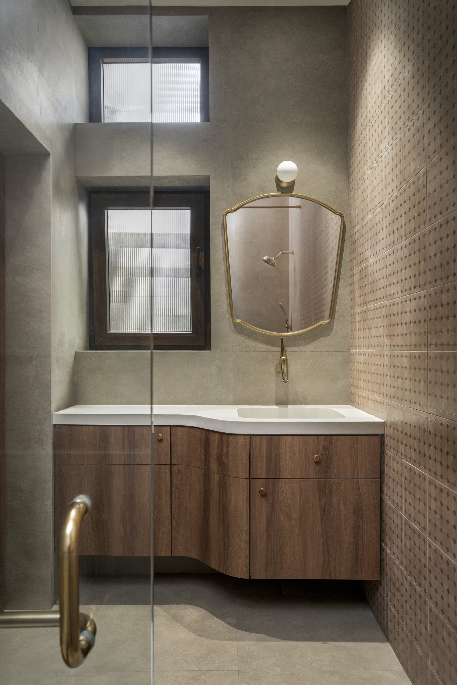The mother's bathroom, with a curved timber vanity and a brass-framed mirror against a patterned tiled wall