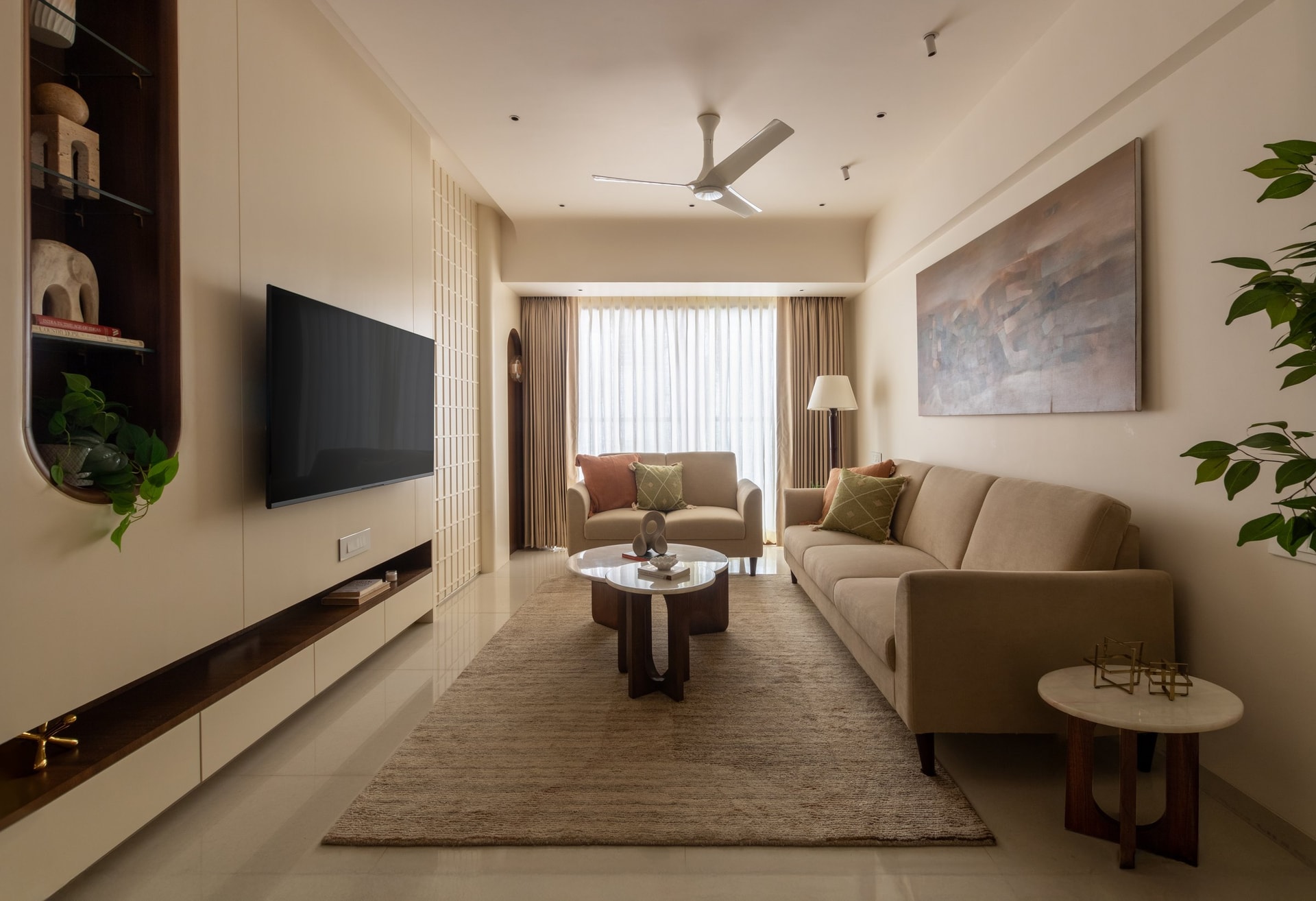 The living room, where a sweeping media wall conceals a low beam and introduces the home's recurring language of curves