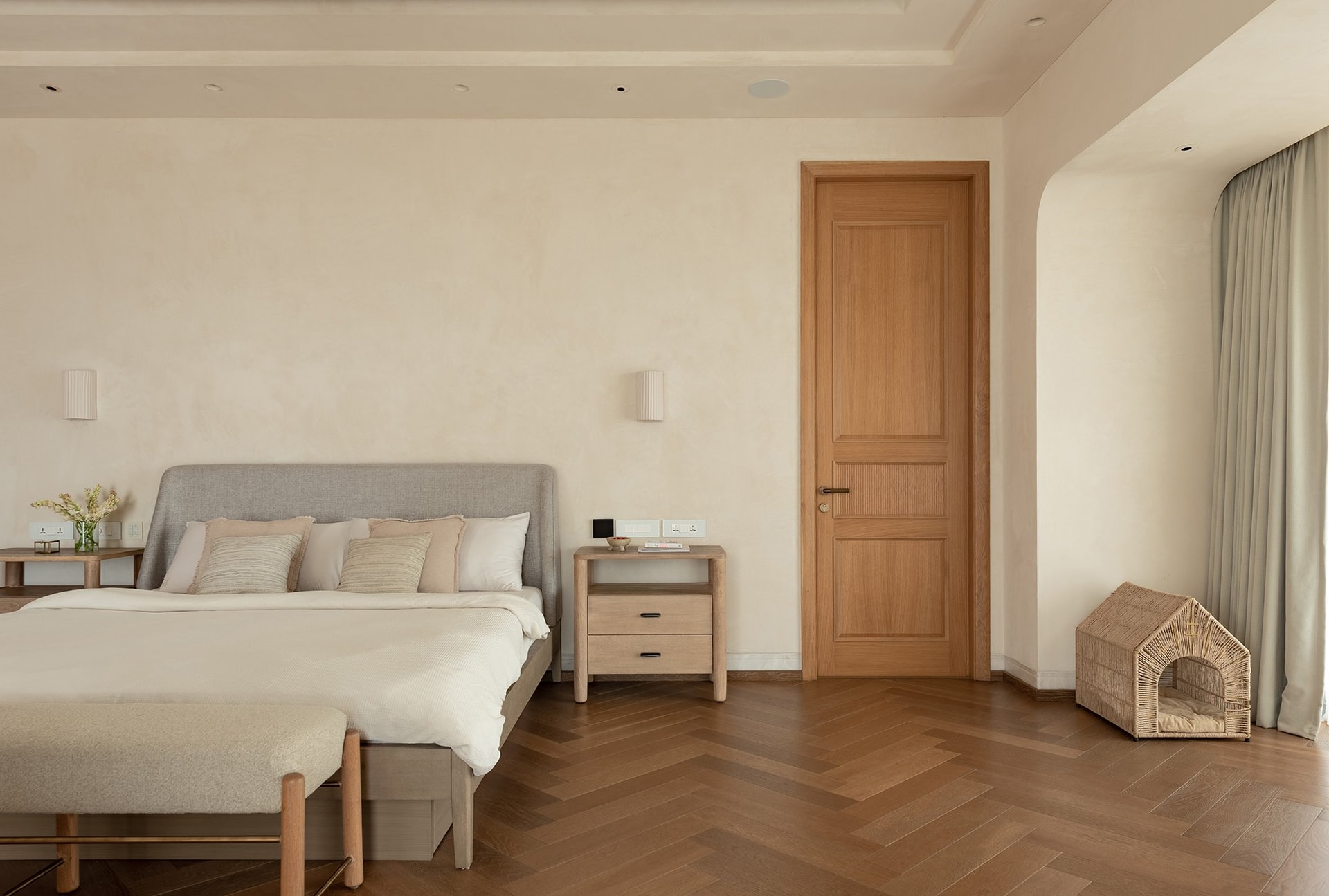 A quieter view toward the ensuite door, where a woven pet house signals that the suite was designed with Cosmo in mind