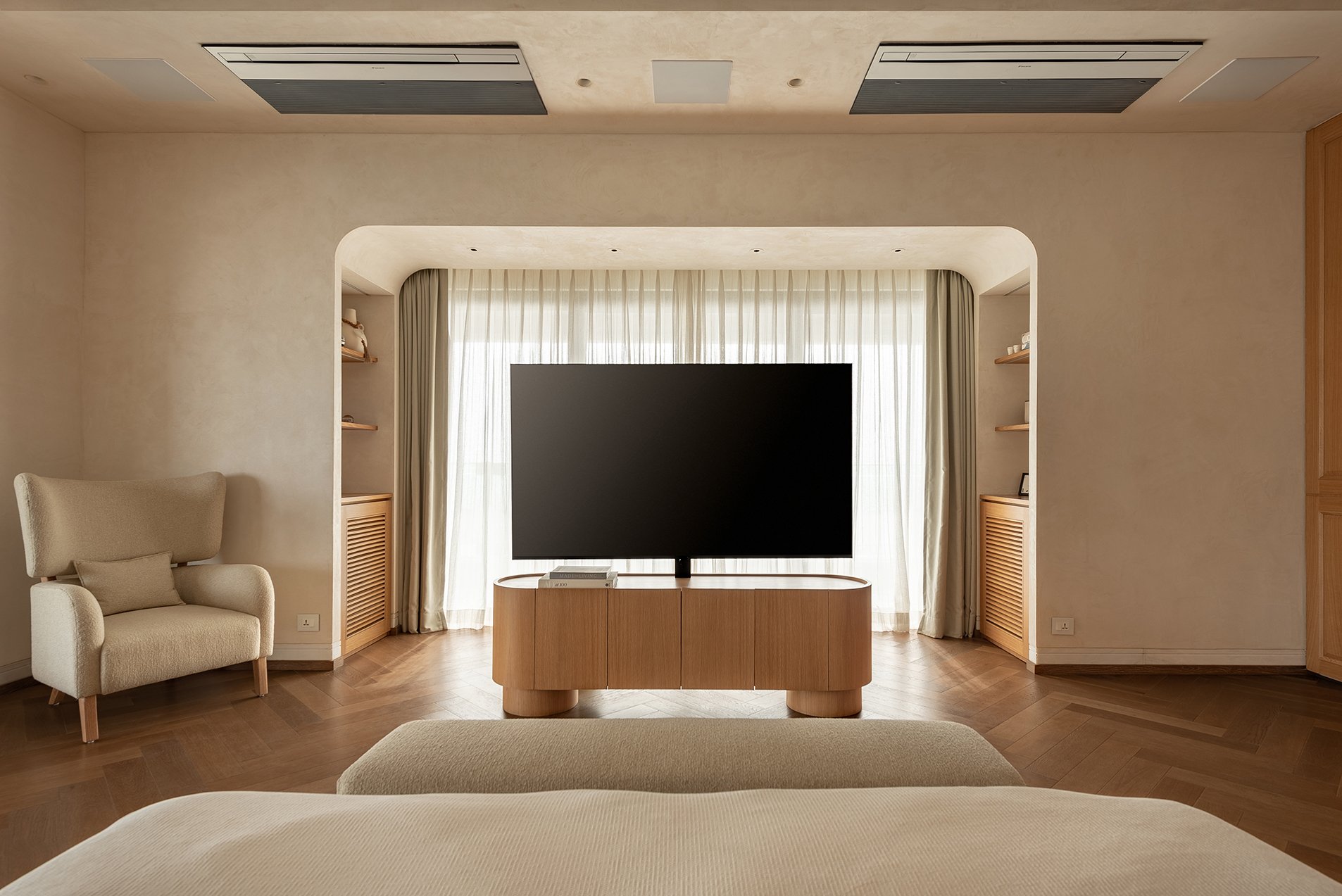 The media wall, framed by an arched plaster opening and flanked by louvred oak cabinets