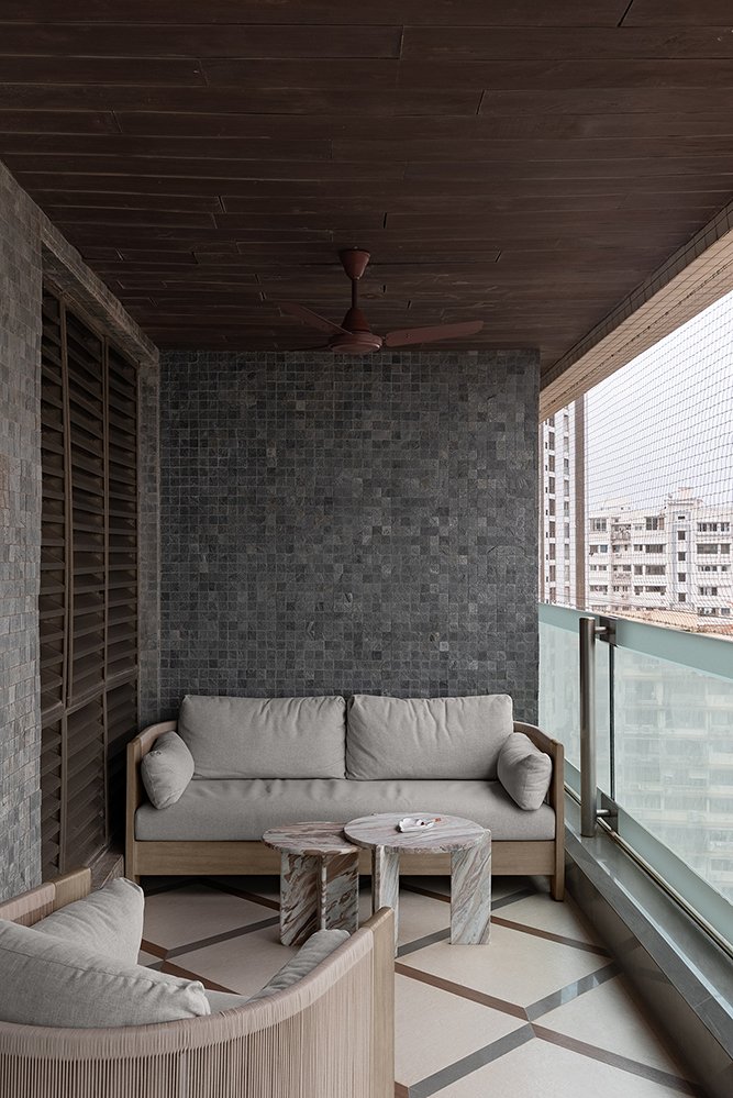 The second balcony, grounded by a dark stone-mosaic wall and a slatted wooden ceiling