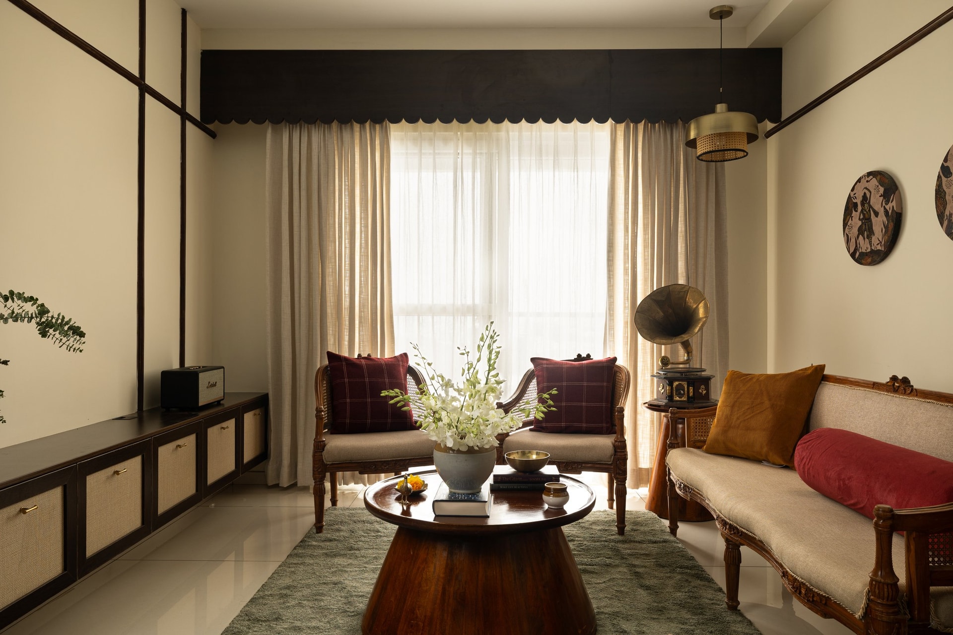 The living room, where dark linear wall trim, carved cane furniture and a moss-green rug set the home's defining register