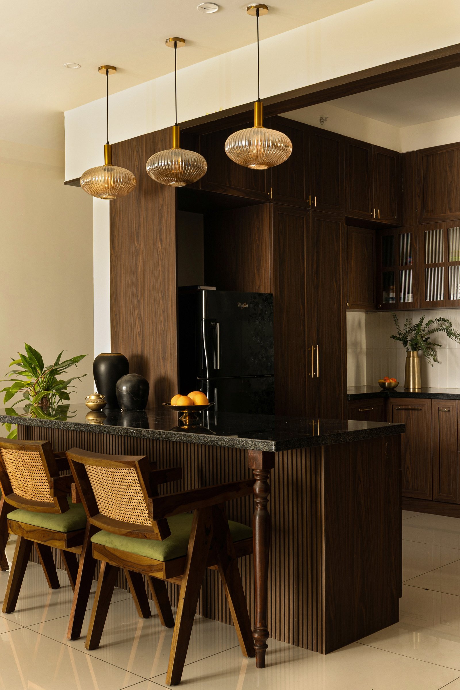 The dining counter, anchored by a fluted wooden island and three ribbed amber-glass pendants