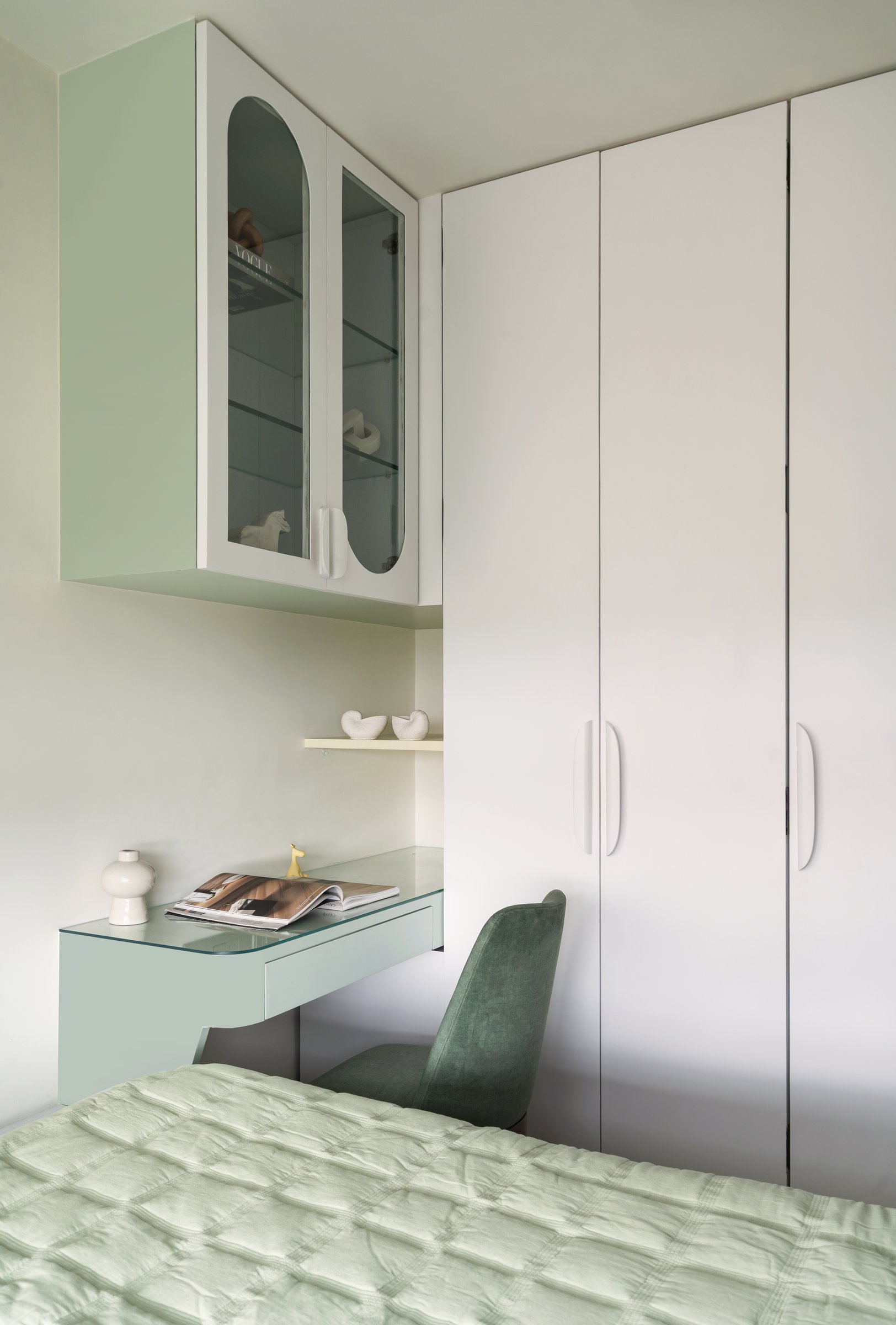 The study corner in the second bedroom, with a glass-topped sage desk and a glass-fronted display cabinet
