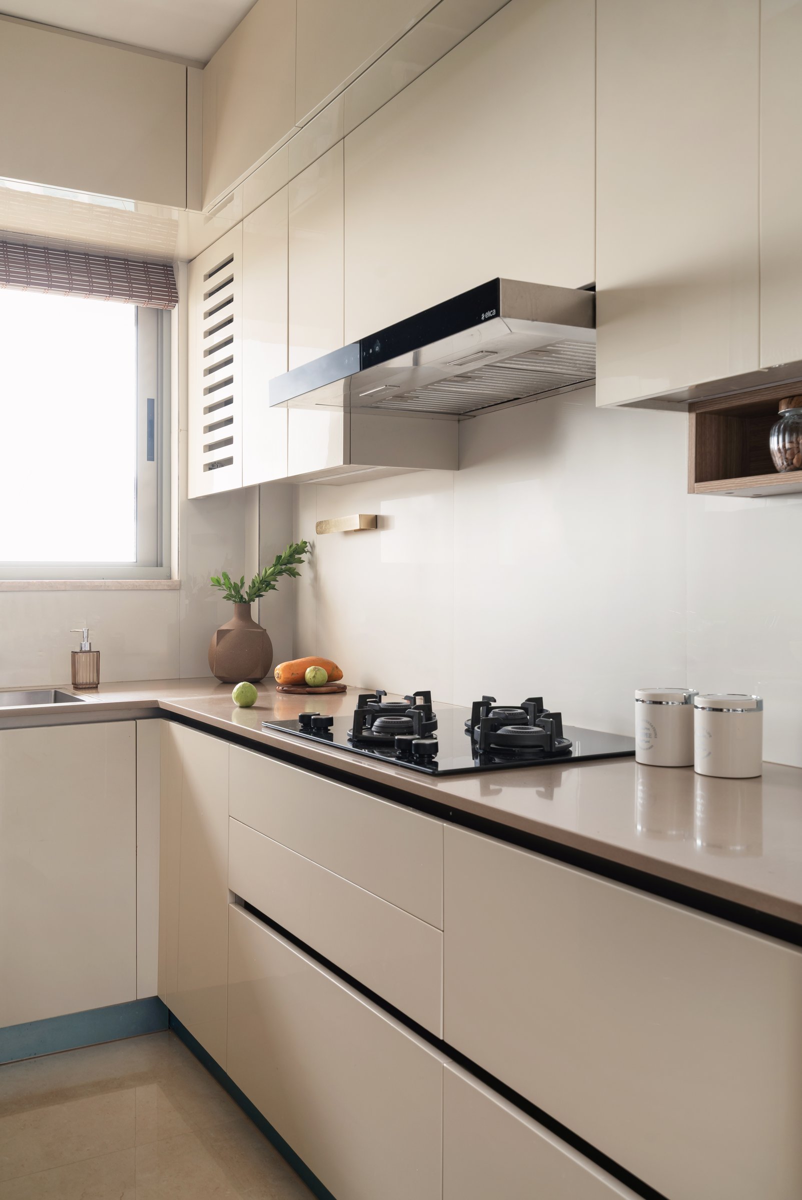 The kitchen, where glossy cream cabinetry and a stone-toned counter prioritise calm and function