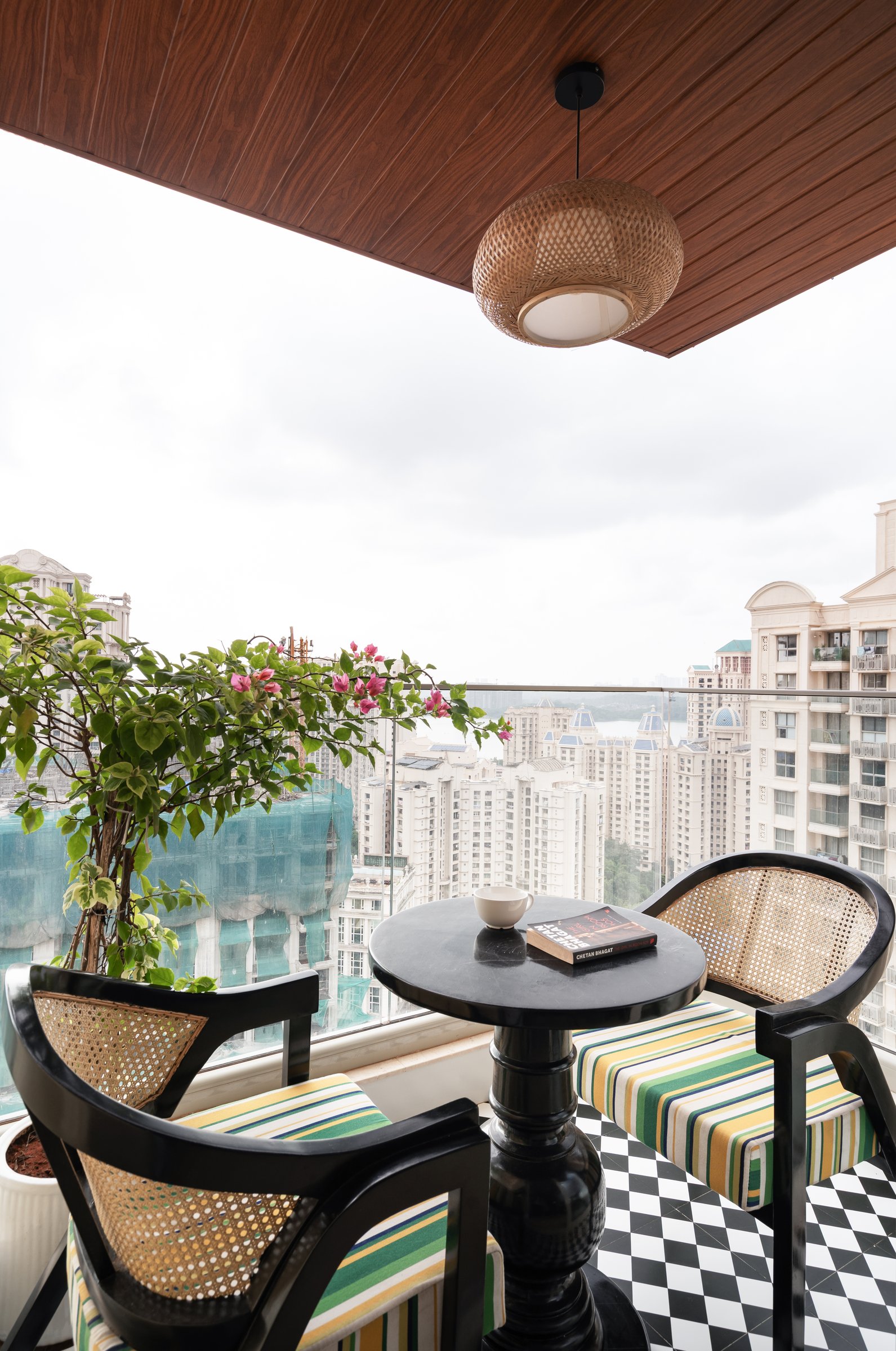 The balcony, where a wooden-planked ceiling and chequered floor frame a view of the Hiranandani skyline