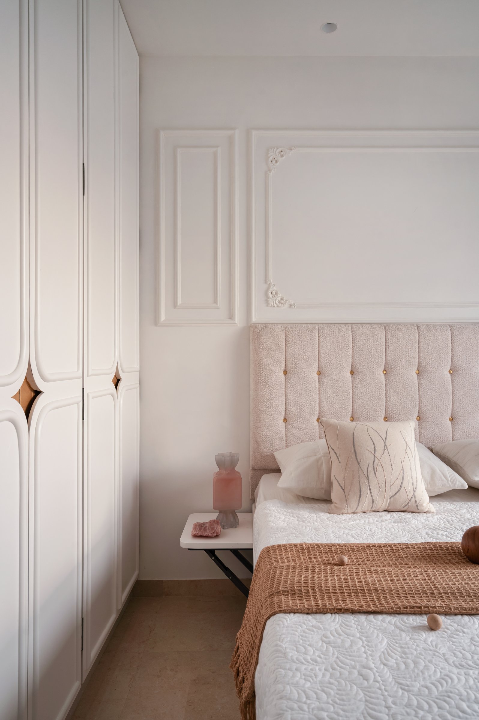 A side view showing the panelled wardrobe and a floating bedside shelf on slim black metal brackets