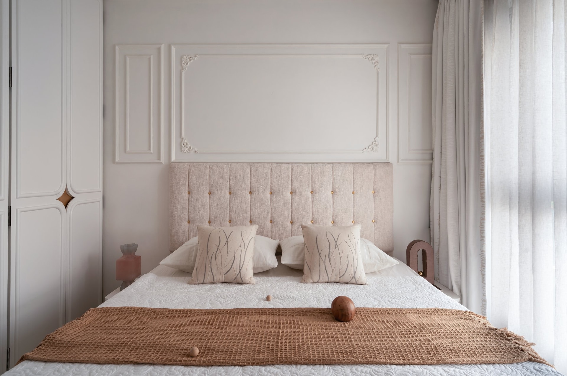 The third bedroom, where a buttoned ivory bouclé headboard meets a moulded white wall panel