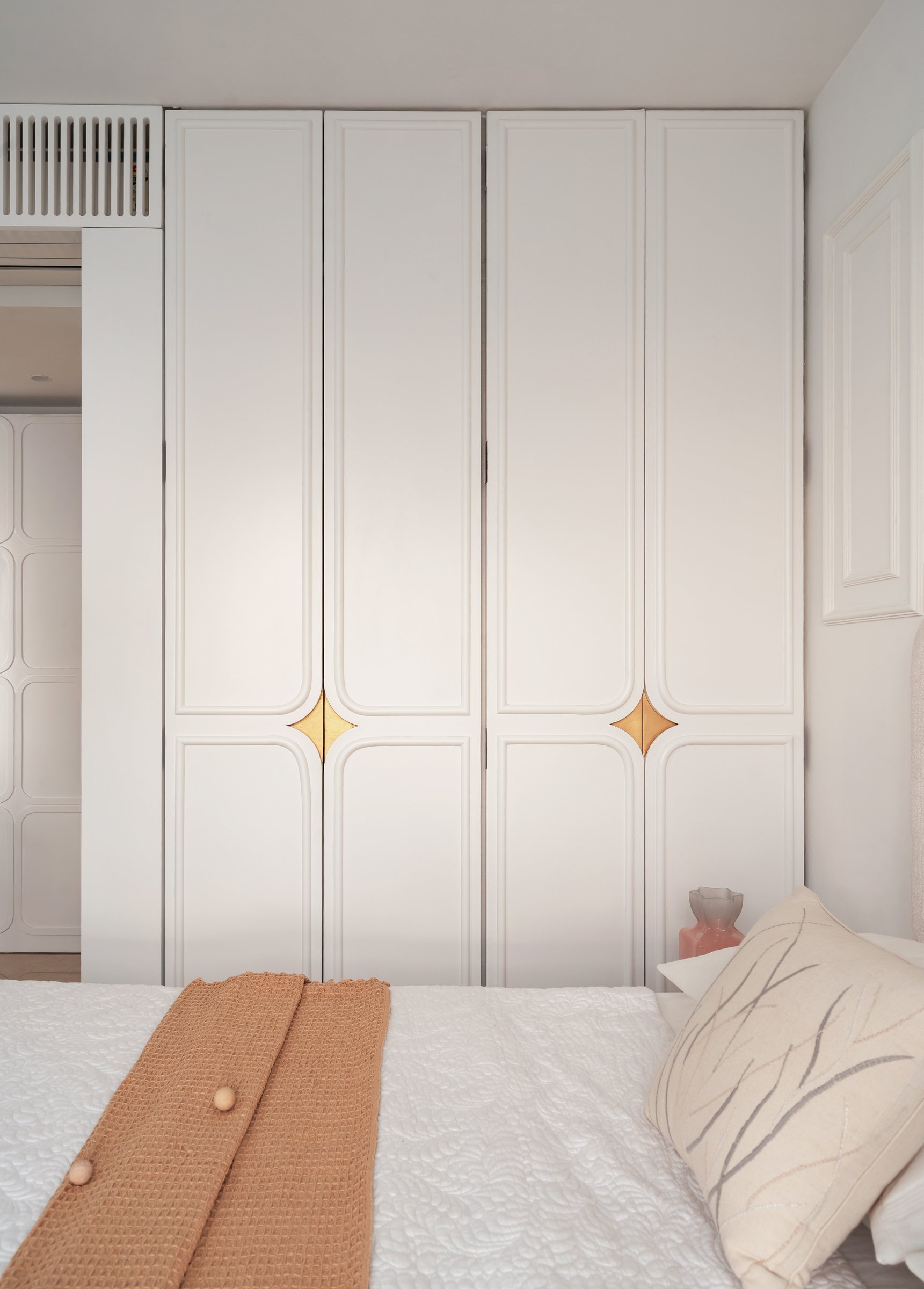 The wardrobe front, each tall door marked by a small brass four-pointed star inlay