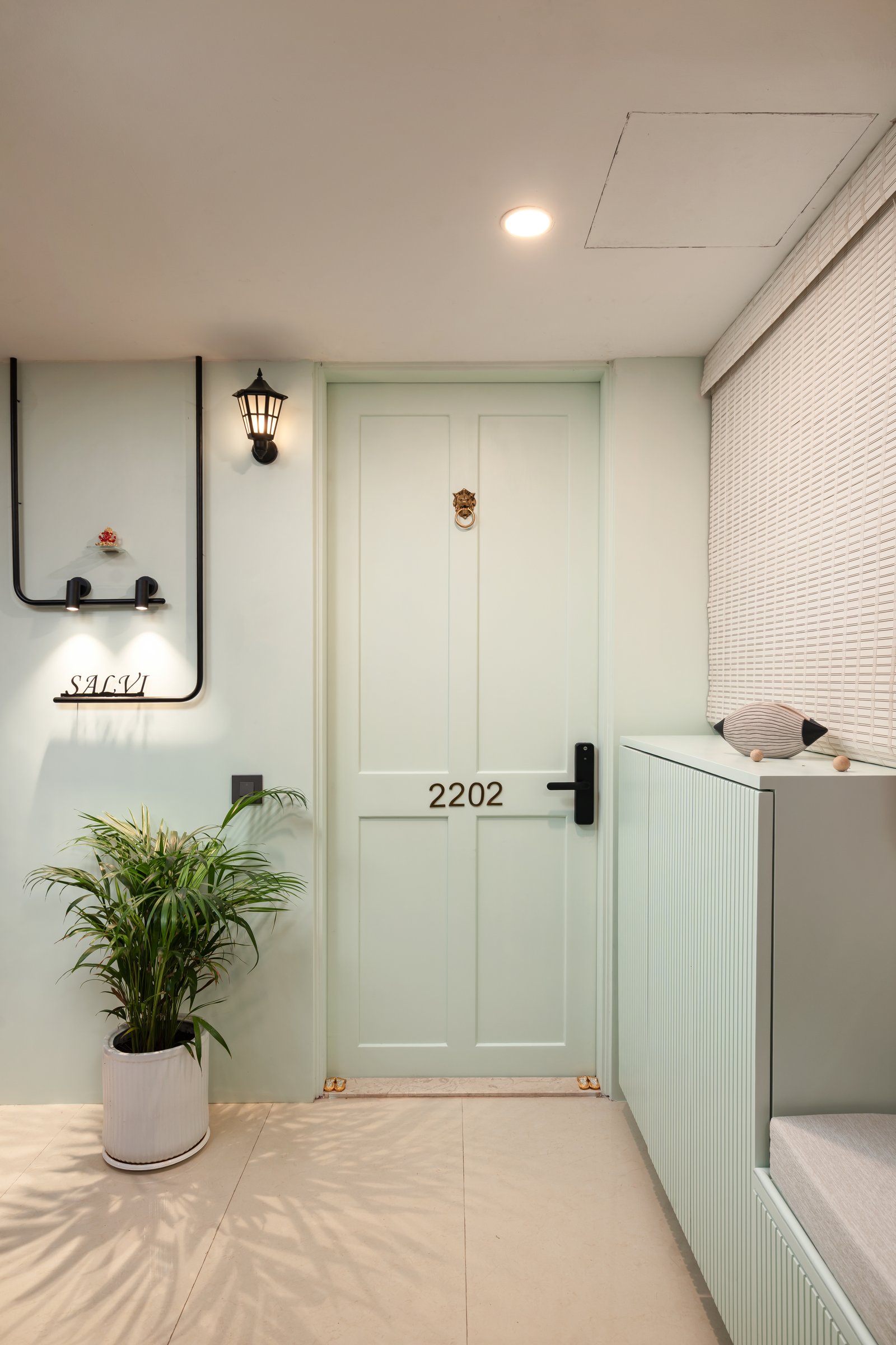 The entrance, where a mint-green panelled door and ribbed cabinet-bench introduce the home's quiet palette