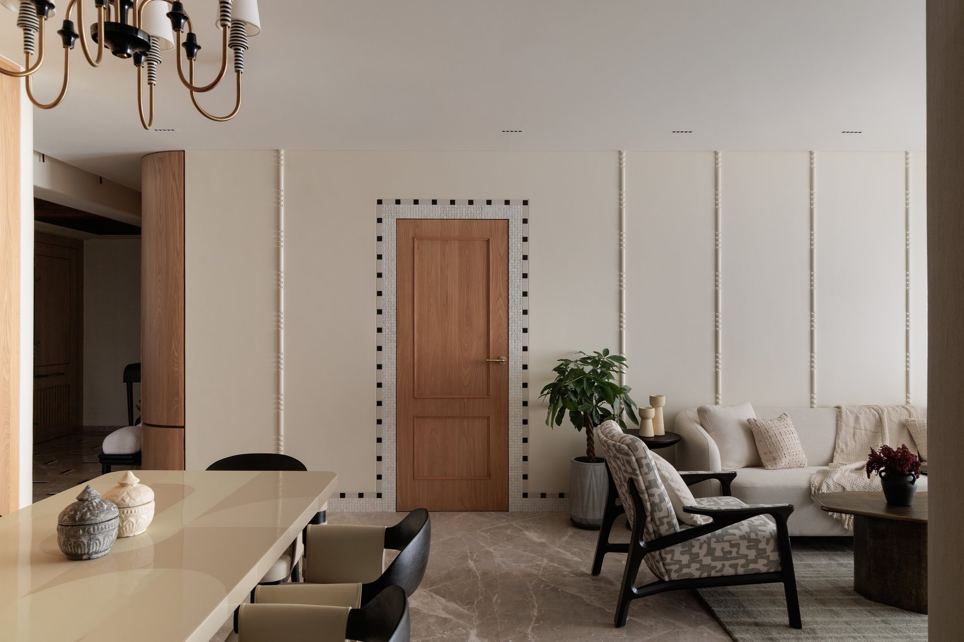 The living and dining volume, defined by full-height upholstered wall panels articulated with slim reeded battens and a single door drawn into the composition