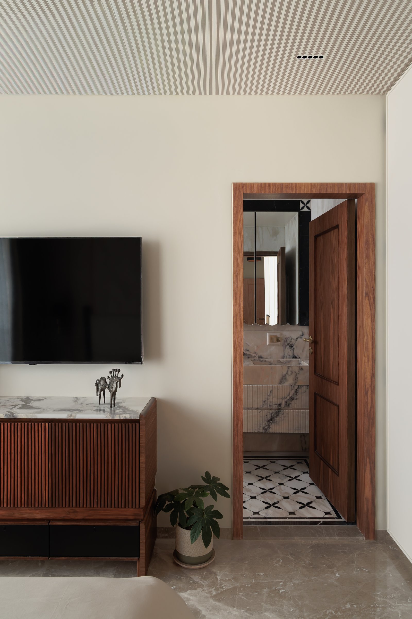 The reeded walnut media console, opening onto a bathroom in richly veined pink-and-grey stone