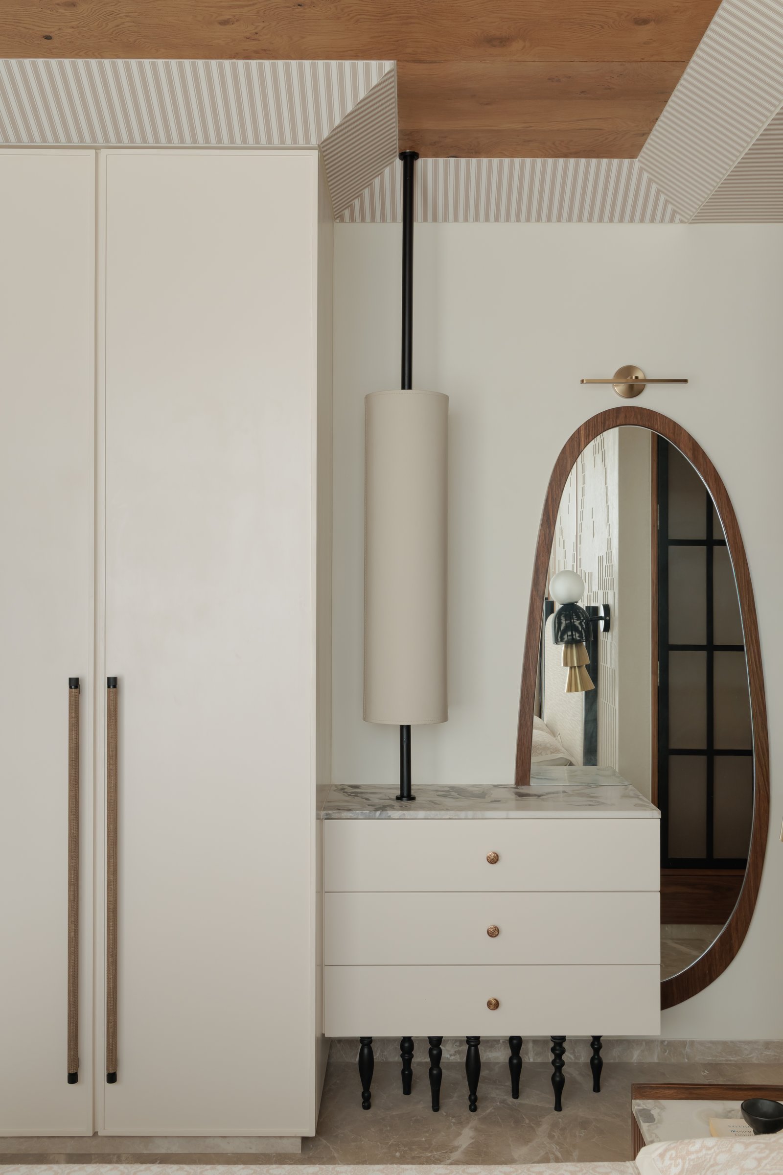 The master vanity composition, with a veined marble counter lifted on turned blackened legs and an elongated walnut-framed mirror