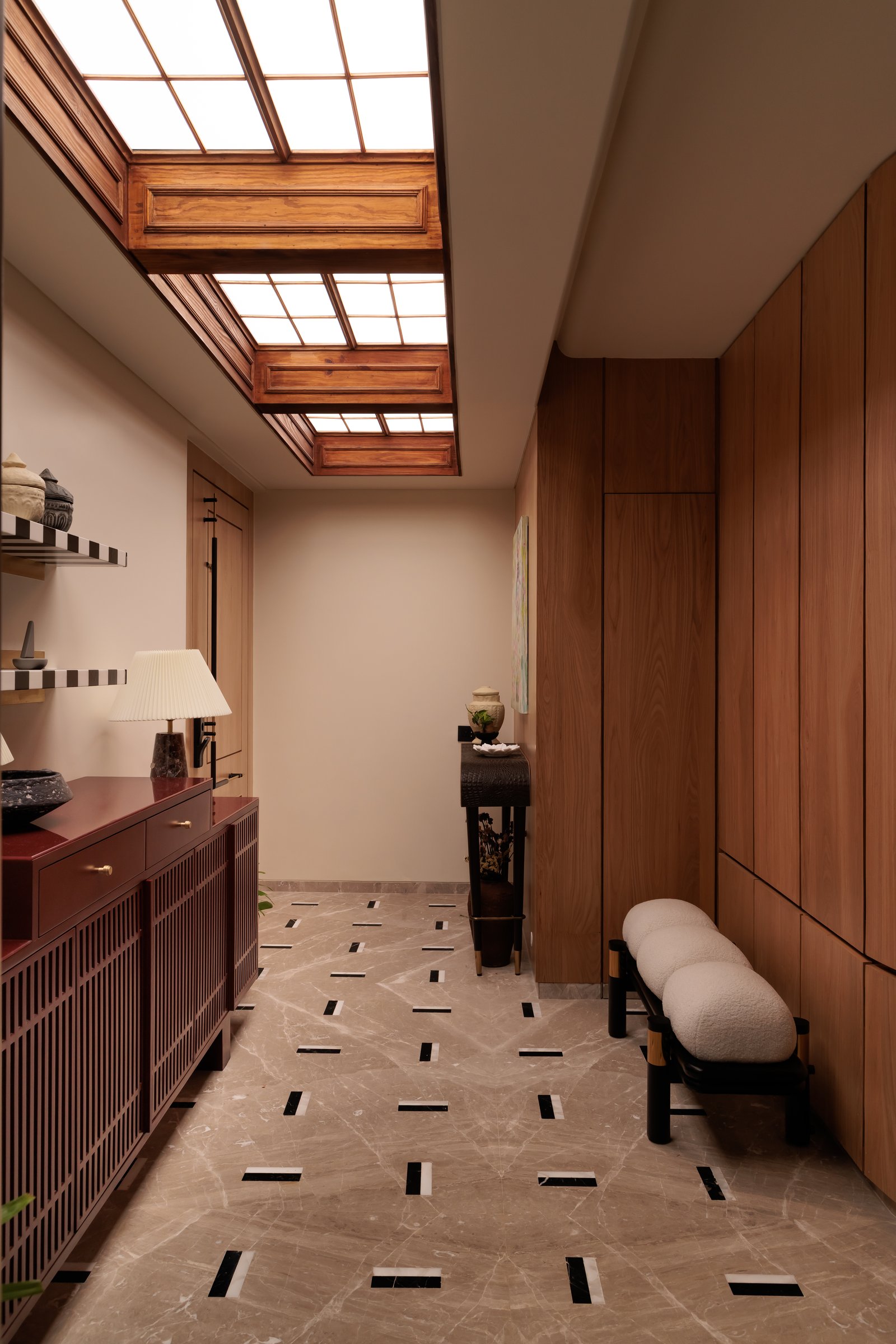 The entry foyer, where a backlit sunroof system of panelled wooden frames mimics true daylight overhead, with marble flooring punctuated by graphic black-and-white inlays
