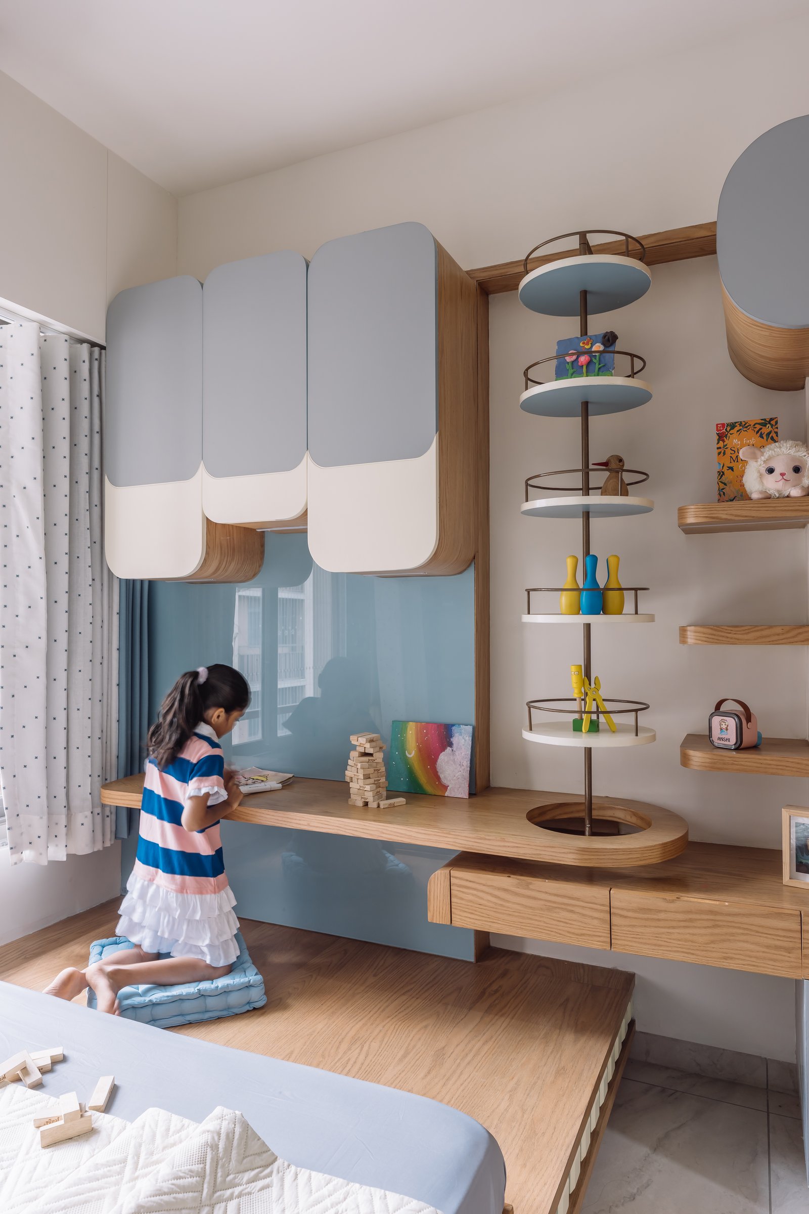 The desk and reflective blue panel in the children's room, where play, storage and study share one architectural vocabulary
