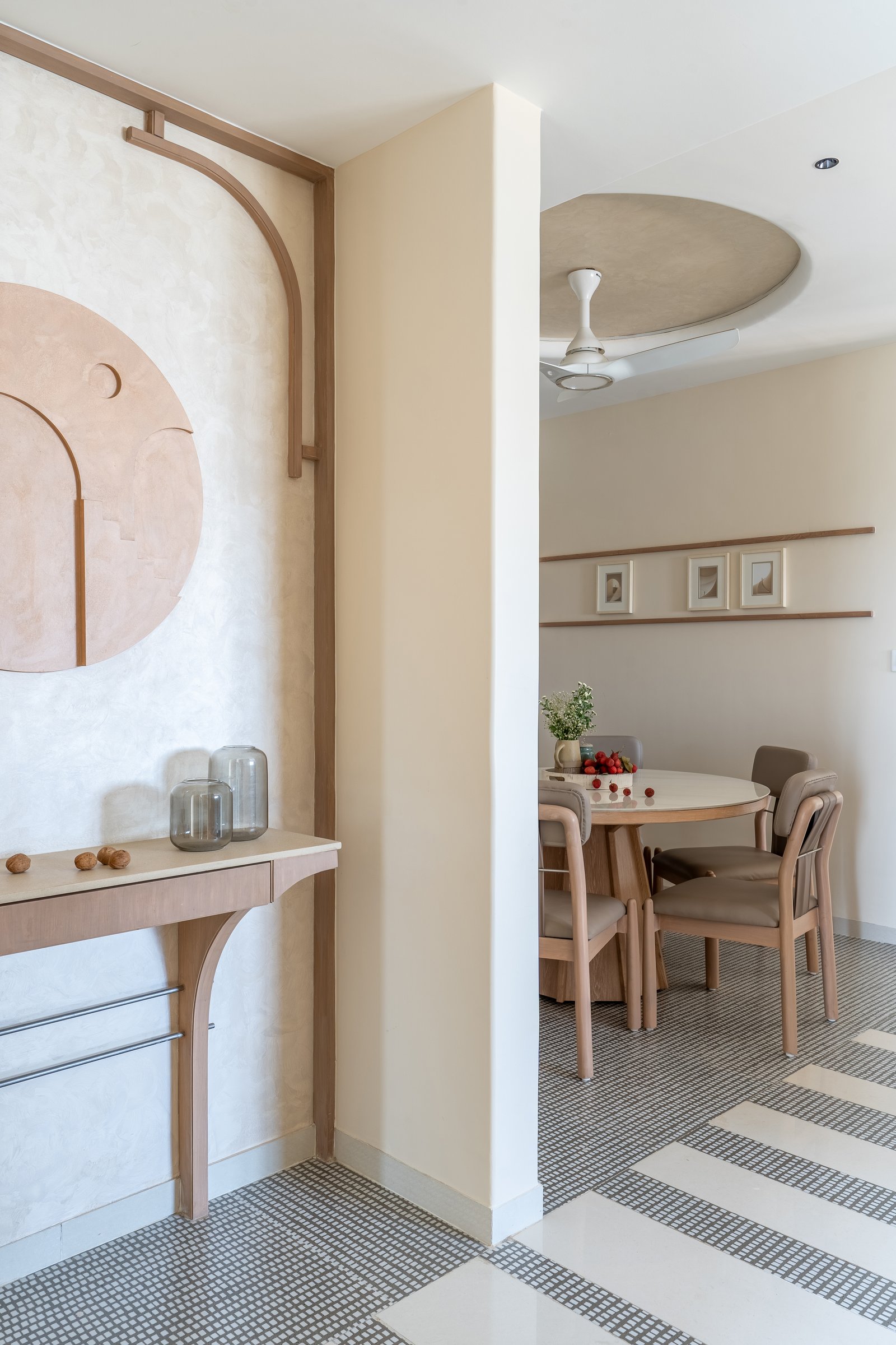 A craft vignette adjacent to the dining, where a slender wooden console sits beneath a sculptural relief in blush-toned plaster