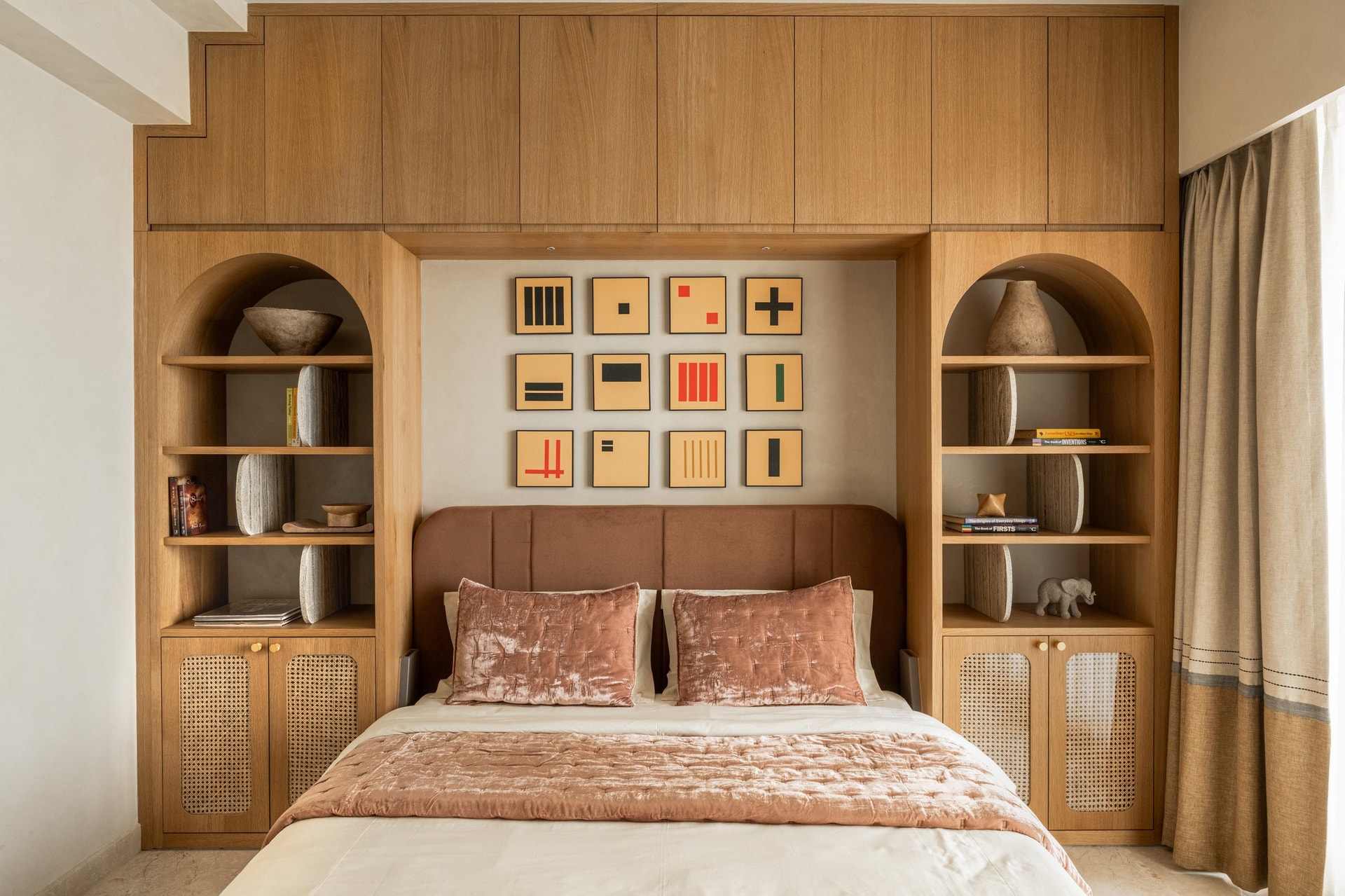The first bedroom, where oak joinery wraps the bed wall in arched niches and cane-fronted cabinets