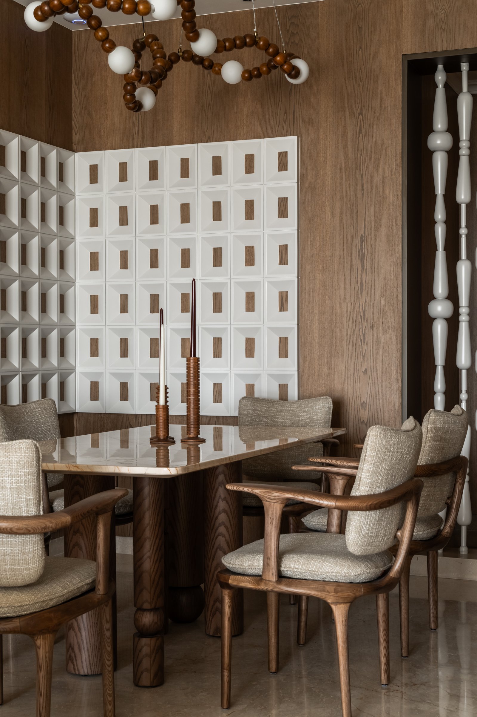 The dining area, defined by a gridded relief panel, turned spindle screen and beaded chandelier