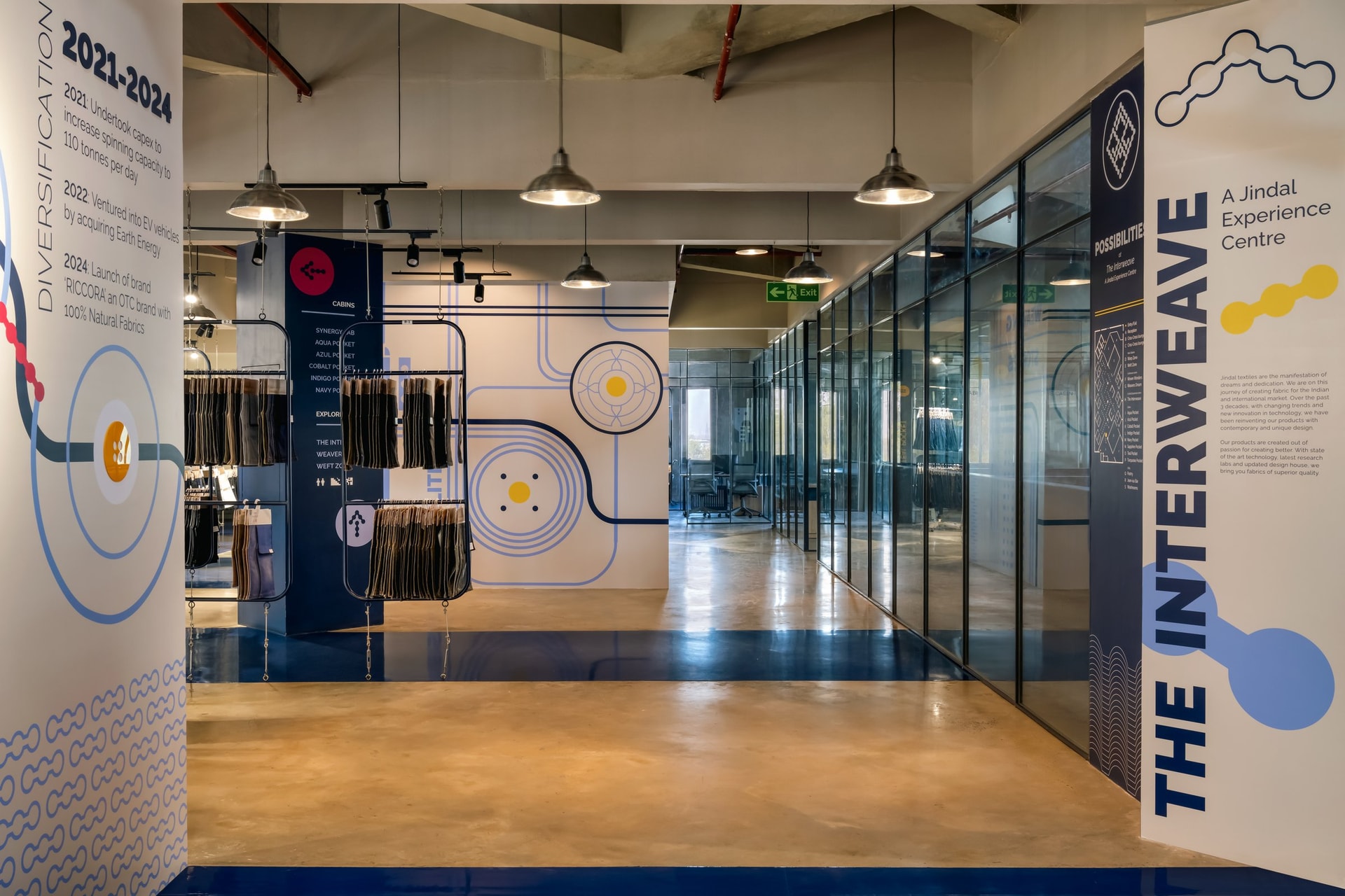 The arrival corridor, where a diagonal band of blue epoxy and a graphic feature wall establish the brand's visual language before the main gallery opens up