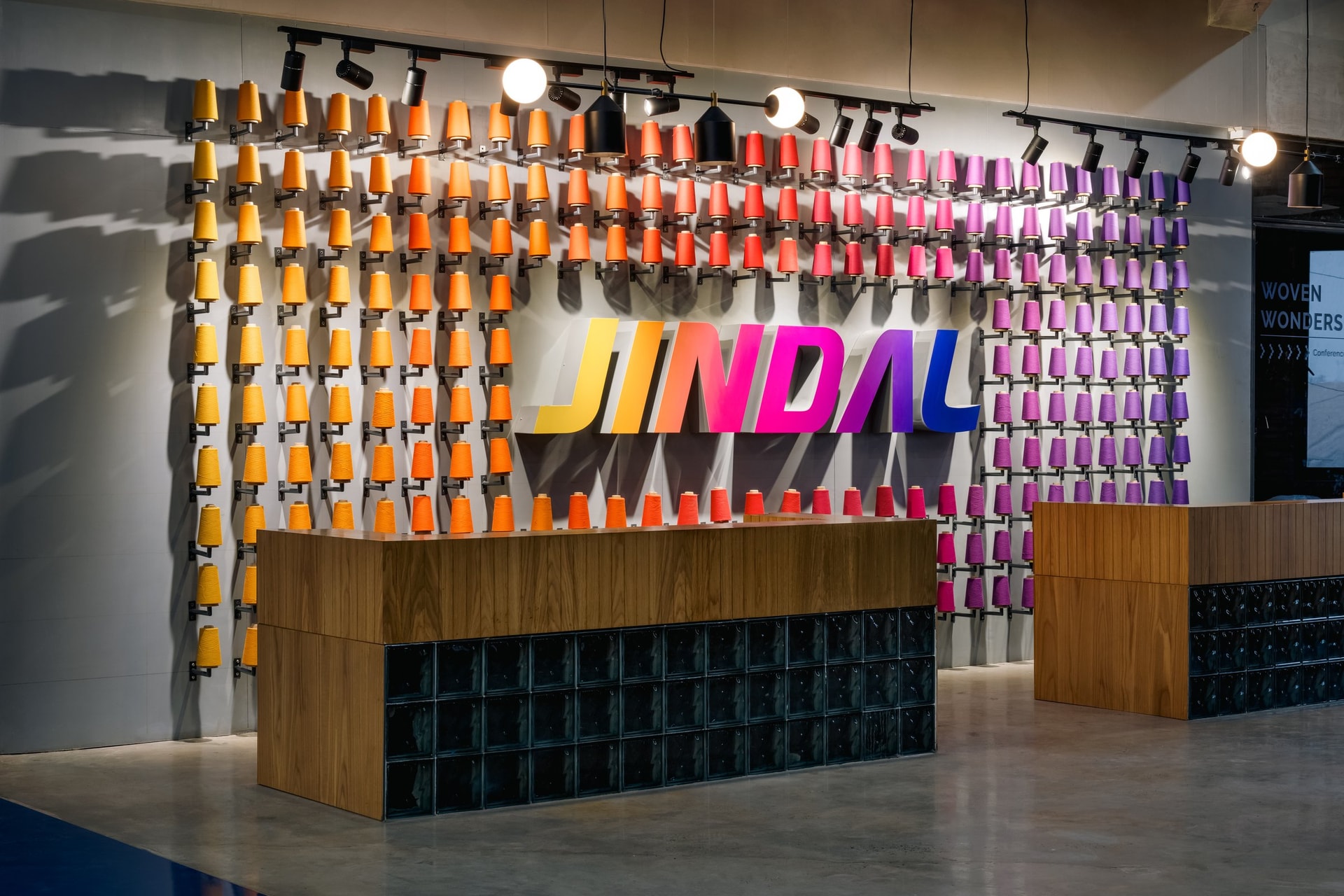 The reception counter, backed by a chromatic gradient of thread spools that translates Jindal's brand identity into raw yarn