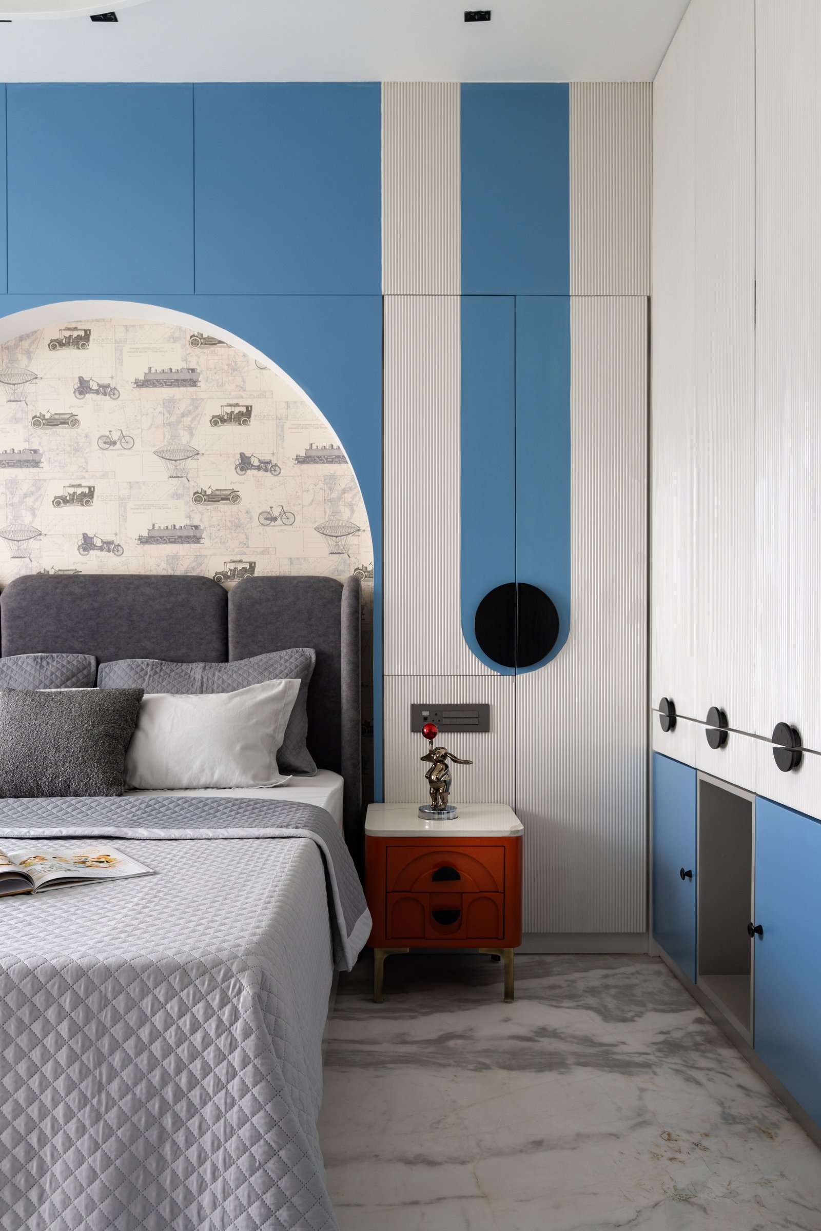 The second children's bedroom, where cornflower blue and fluted white joinery frame a vintage-transport wallpaper niche