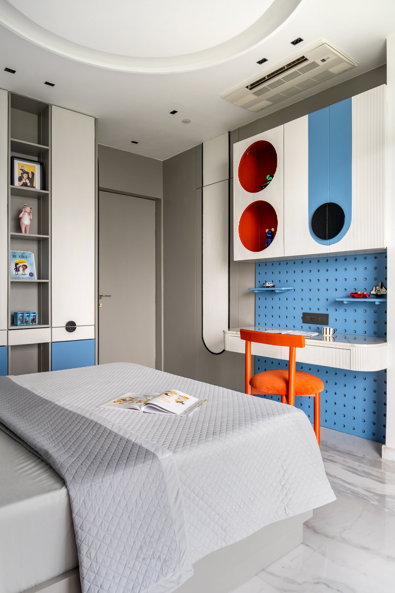 The study wall in the same room, with a blue pegboard surface, terracotta porthole niches and a terracotta chair