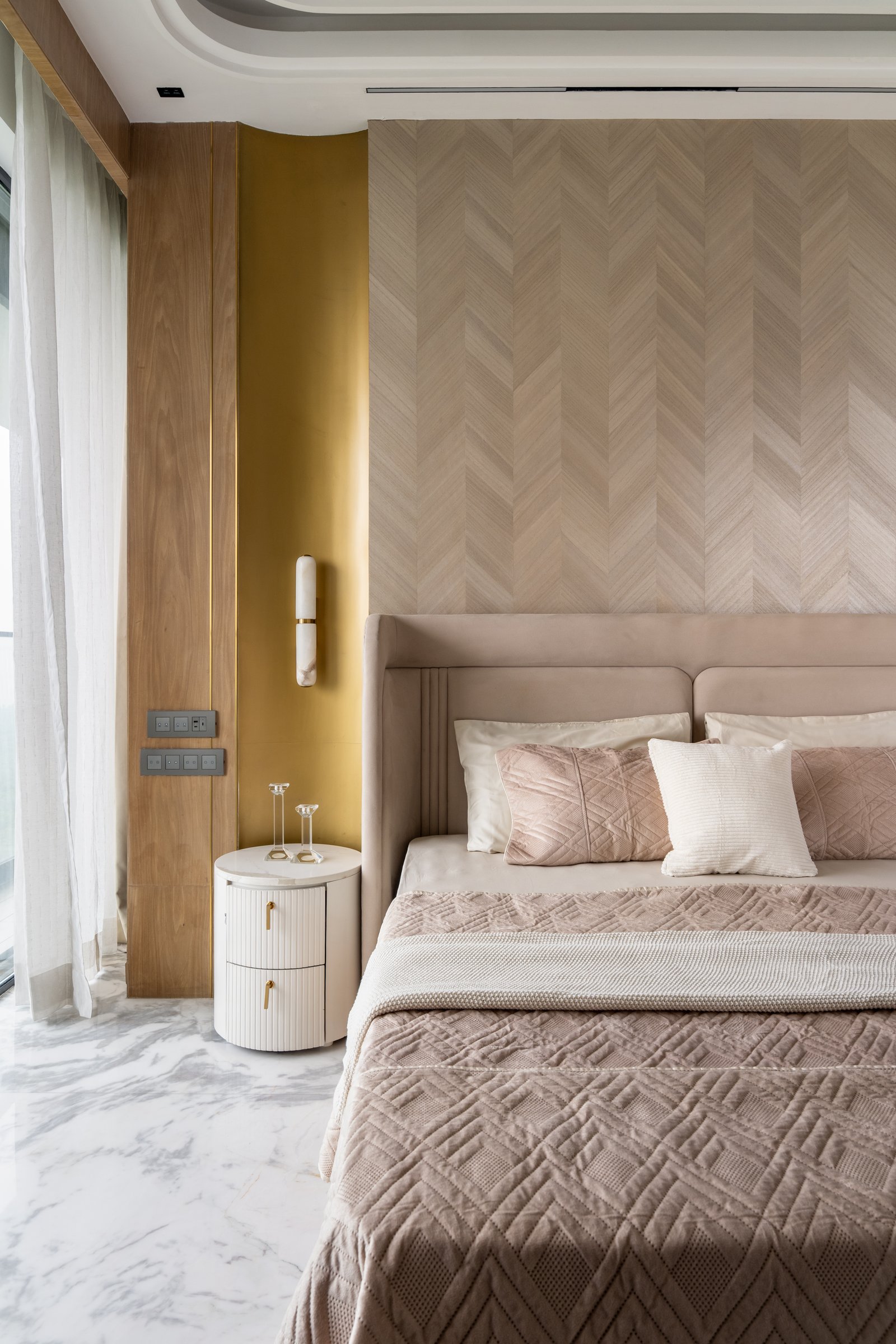 A closer view of the master bedroom's chevron feature wall, alabaster-and-brass sconce and fluted ivory nightstand