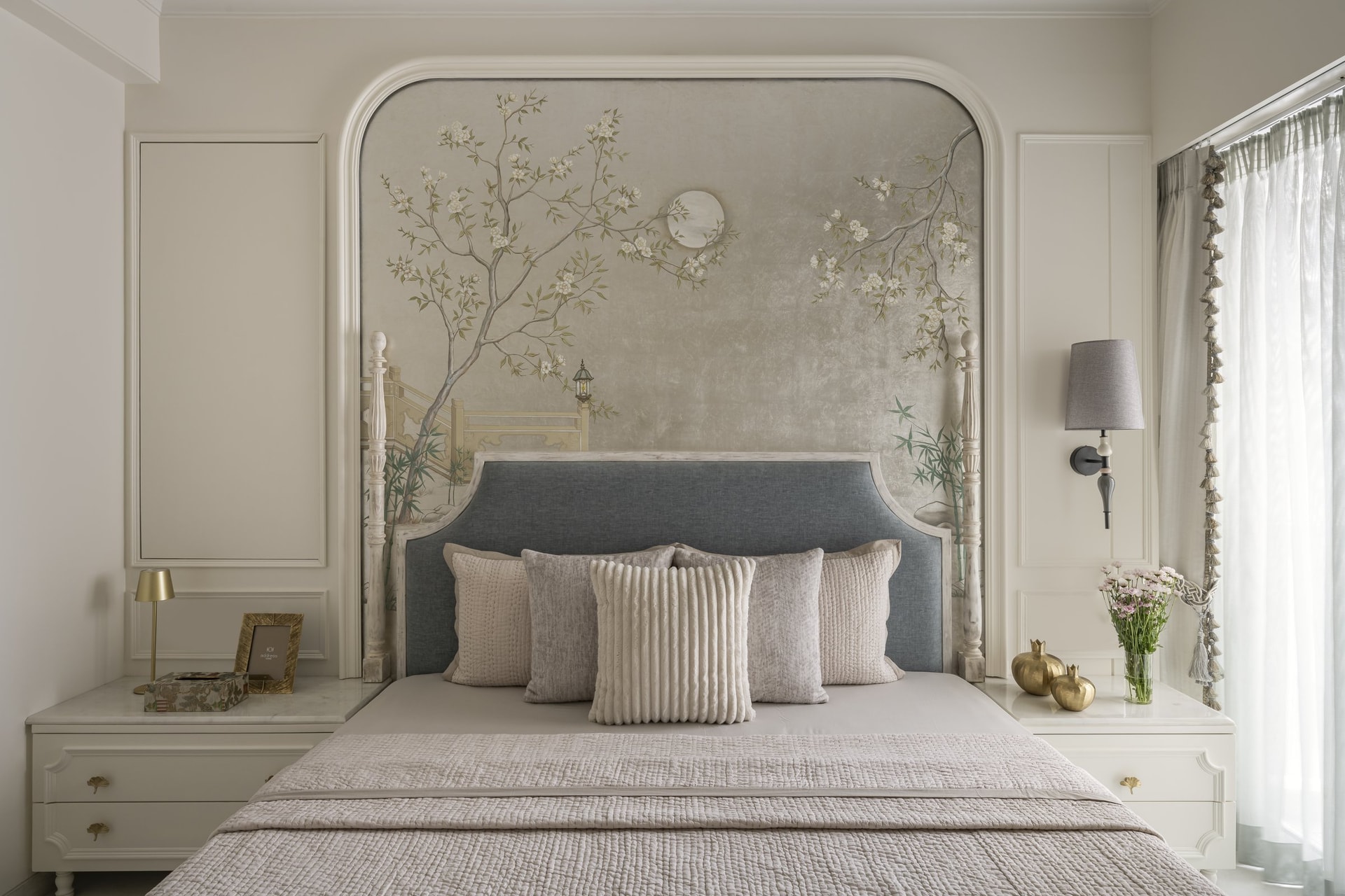 The master bedroom, where a hand-painted Chinoiserie mural by the studio is framed within an arched moulded surround behind the bed