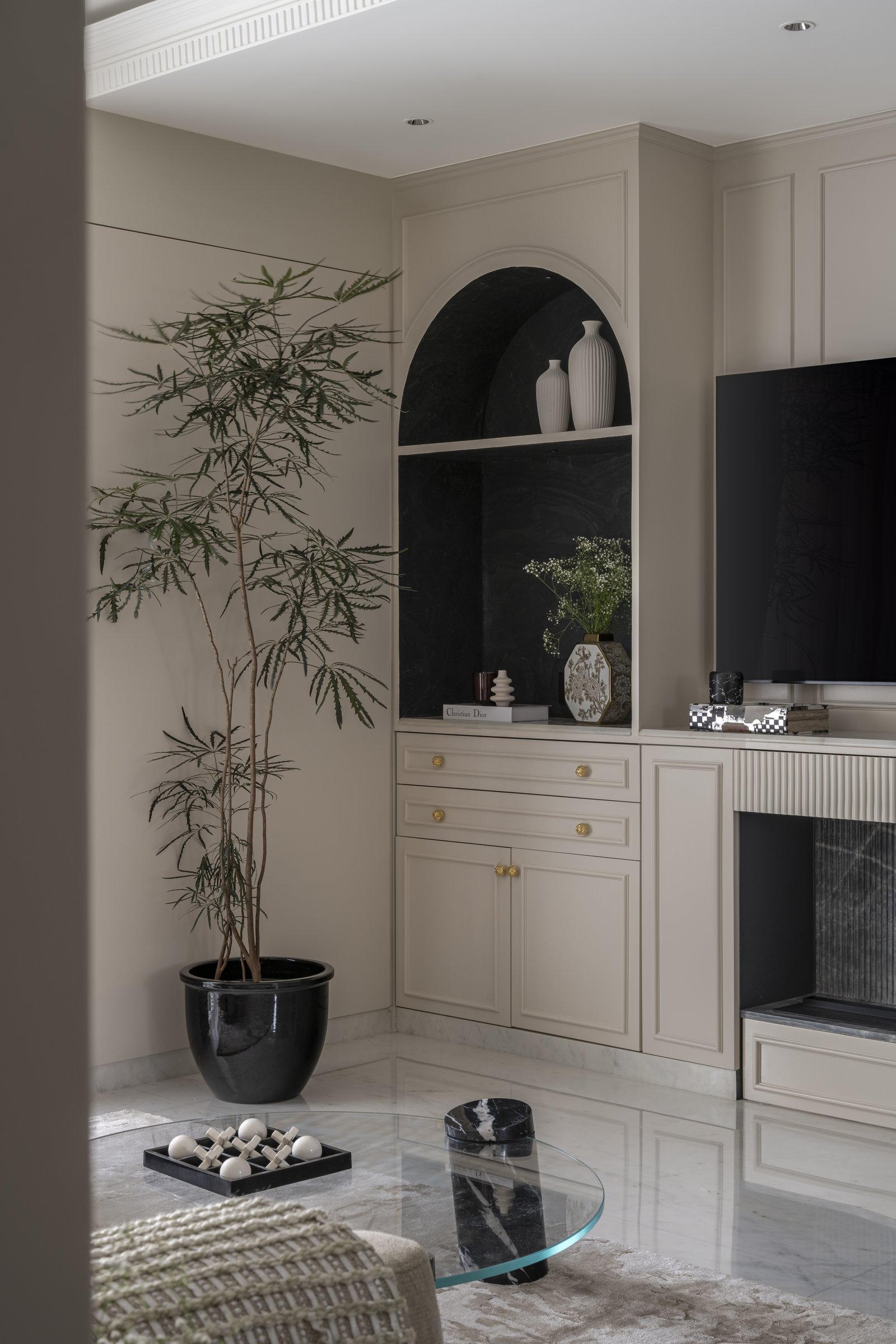 An arched display niche finished in dark stone veneer anchors the corner, set within warm neutral cabinetry with slim brass pulls
