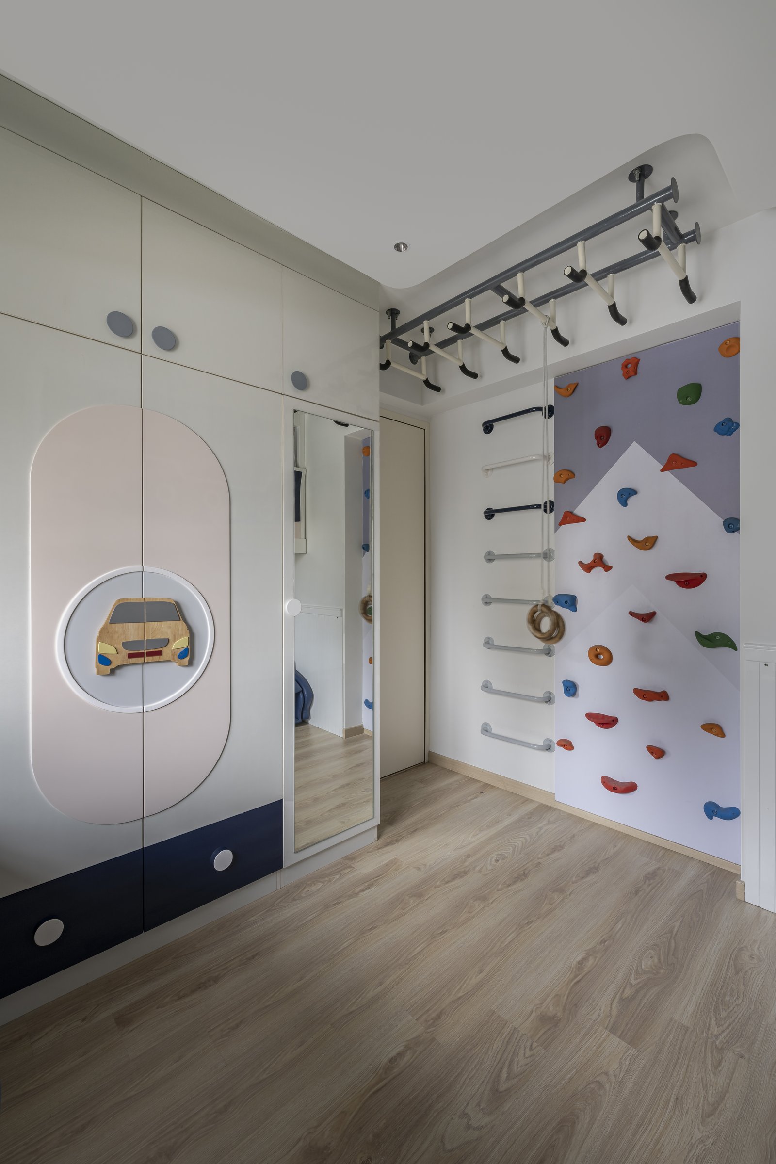 The adjoining play zone of the children's room, with a climbing wall, gymnastic bars and graphic wardrobe fronts