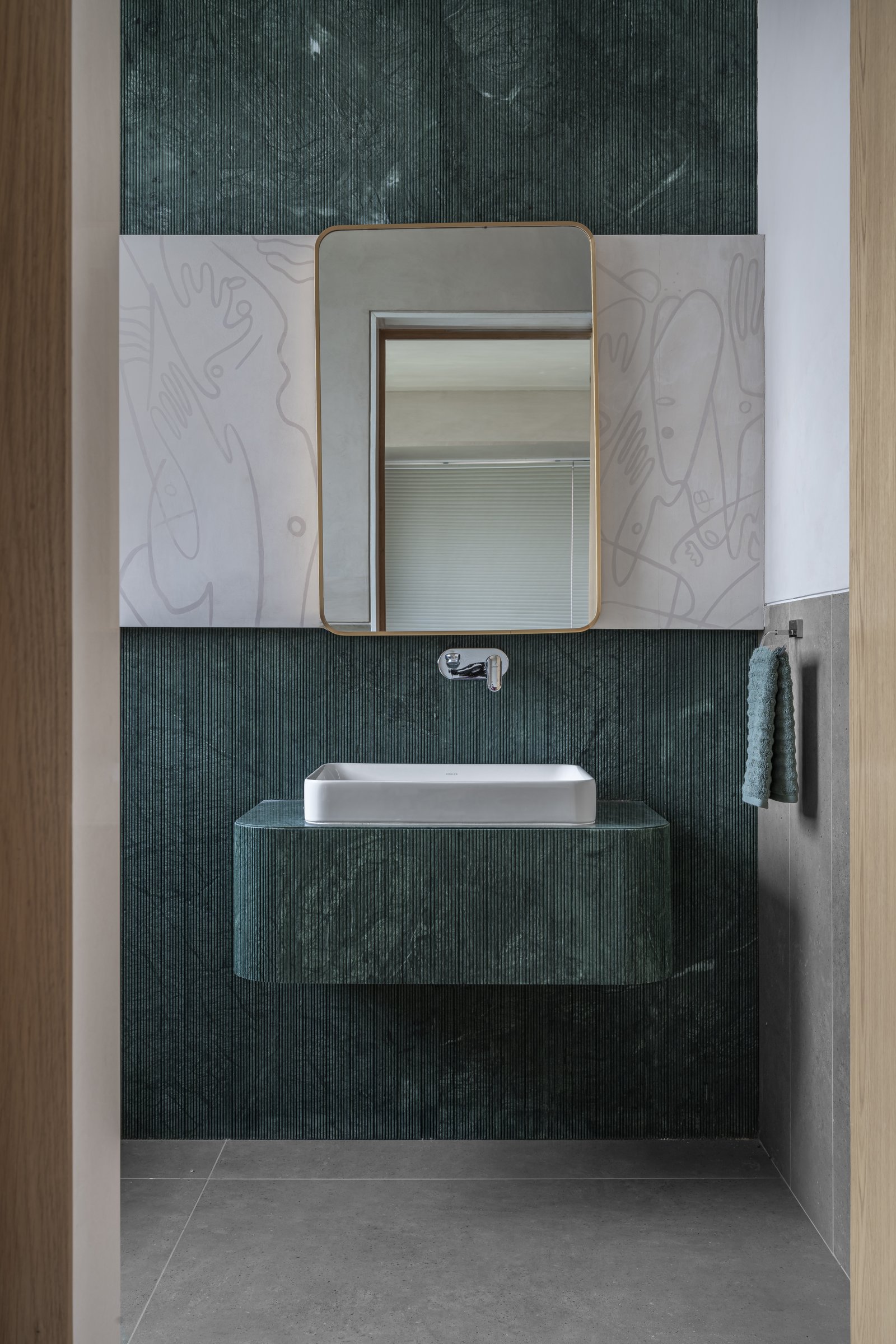 The powder room, where fluted Indian green marble meets a hand-drawn wall panel