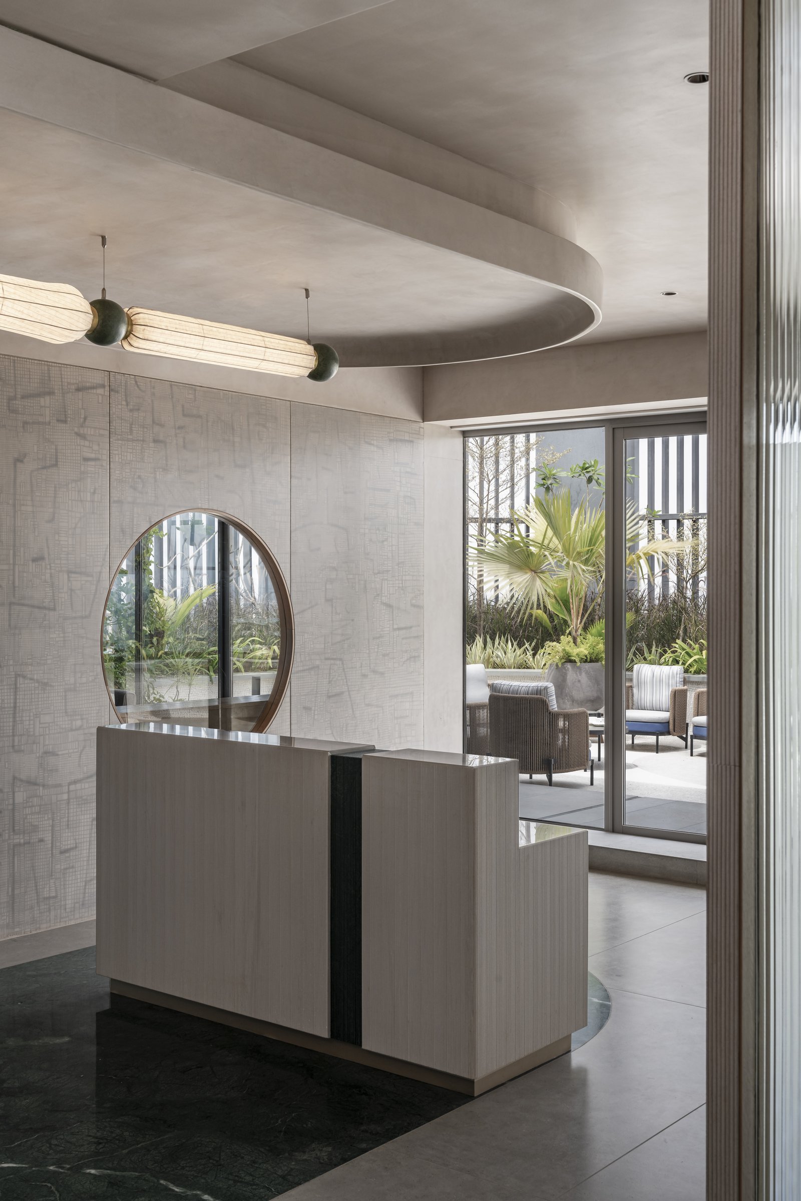 The reception area, where a channelled desk sits before a circular window framing the terrace garden