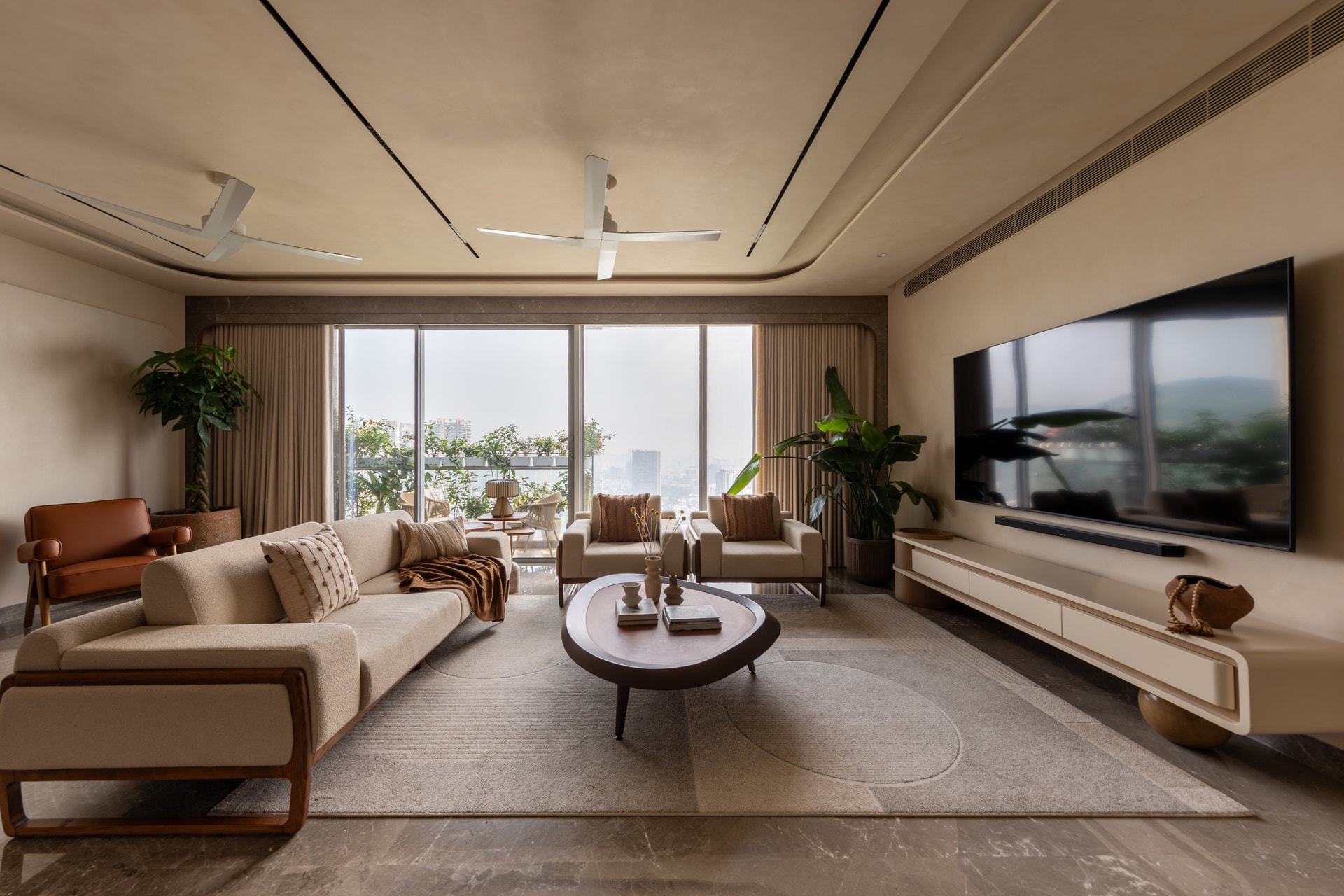 The living room, oriented towards floor-to-ceiling glazing that frames the city beyond