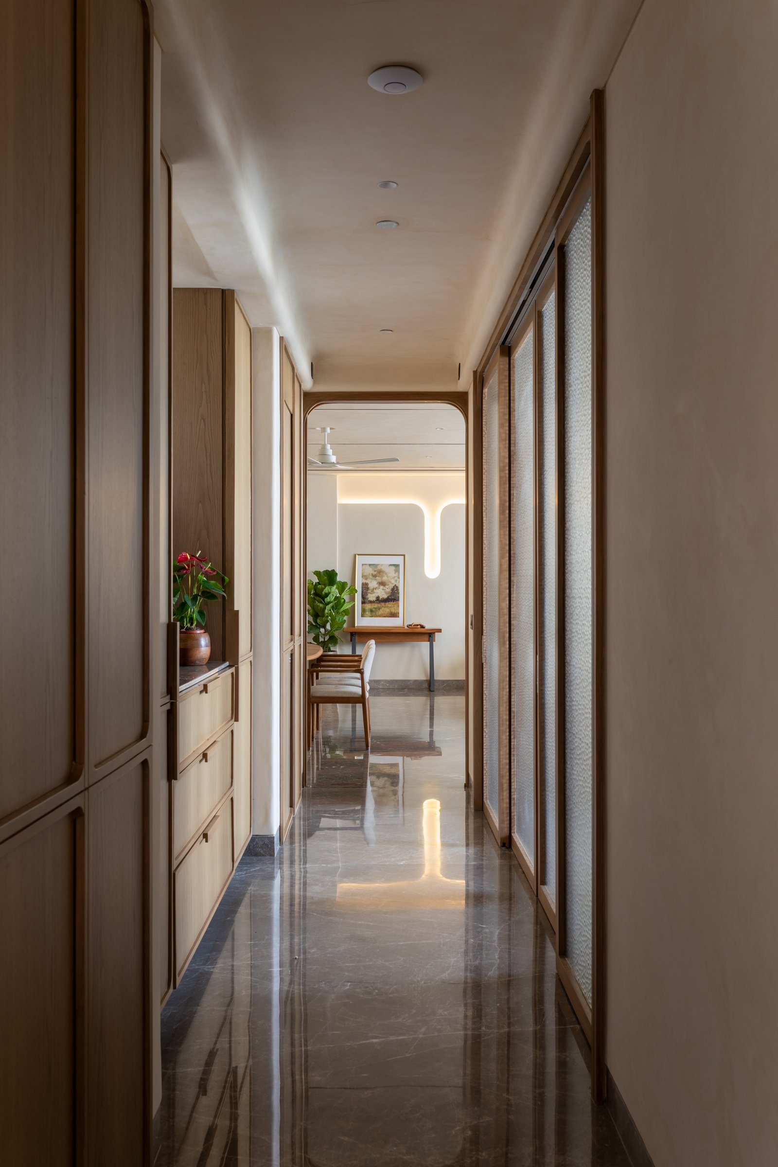 The passage leading to the private wing, drawn forward by a backlit cove detail at its far end