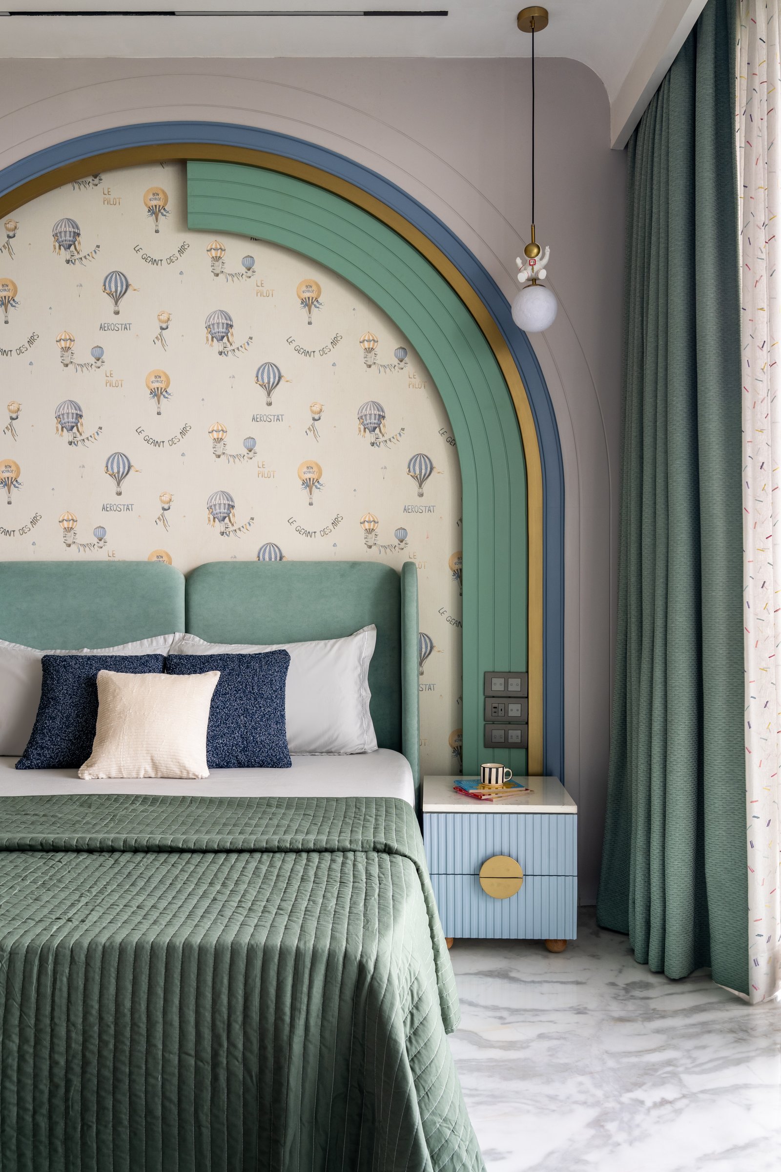 The first children's bedroom, where a layered arched niche in sage, blue and brass frames the headboard wall
