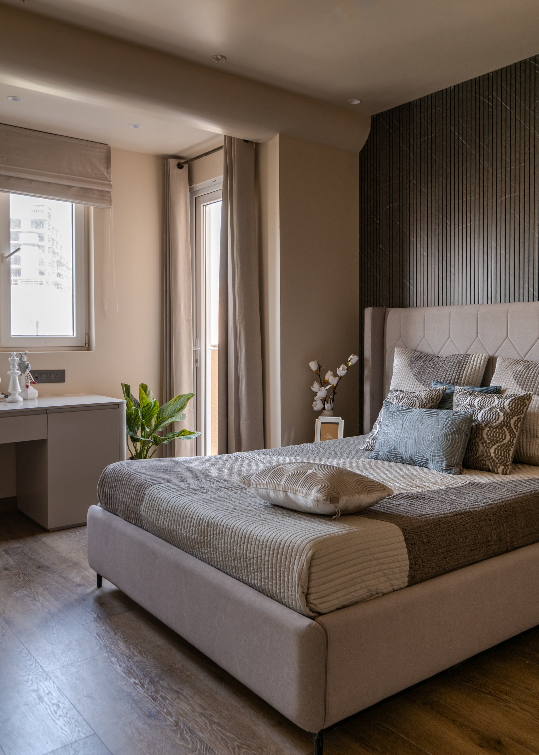 A guest bedroom where a diagonally veined dark stone accent wall anchors the composition behind the upholstered headboard